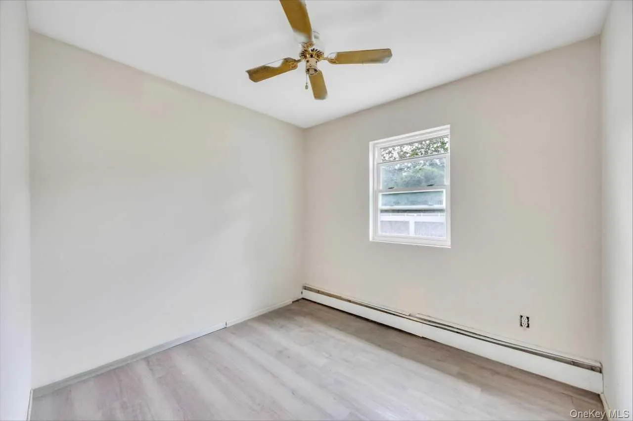 Room featuring light-toned walls, wood-finish flooring, and a ceiling fan Room featuring light-toned walls, wood-finish flooring, and a ceiling fan