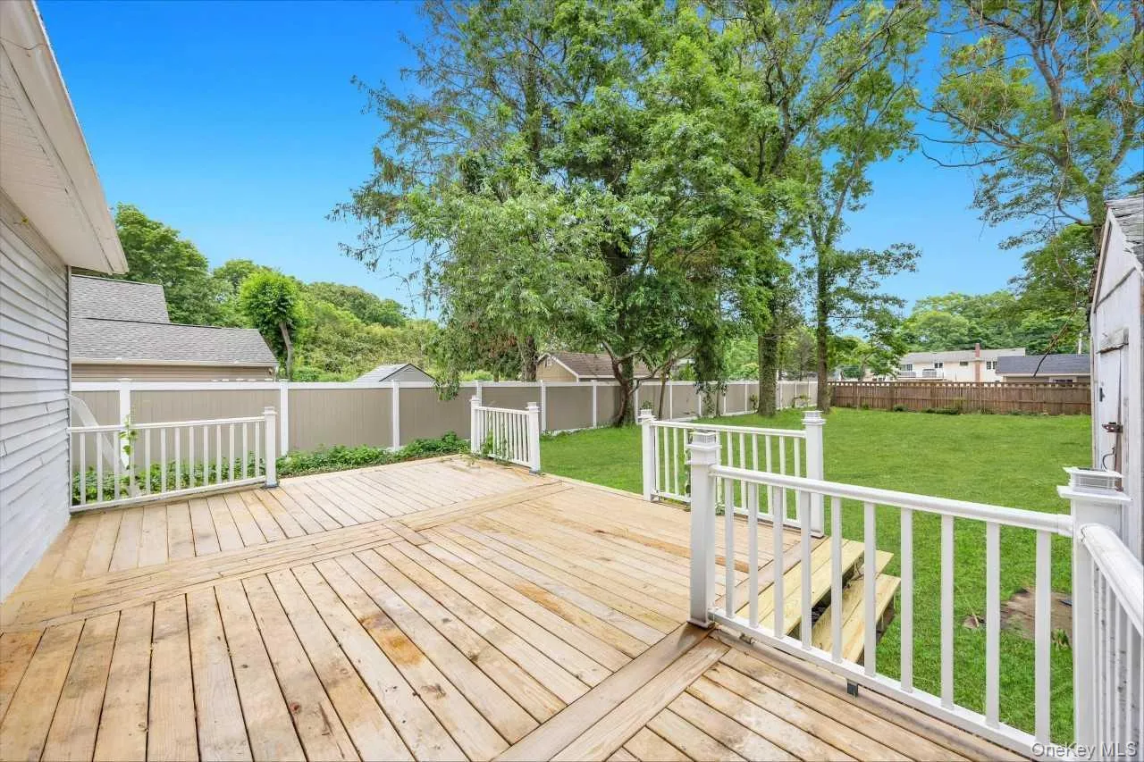 Spacious wood deck with white railings, offering direct access to a large grass lawn Spacious wood deck with white railings, offering direct access to a large grass lawn