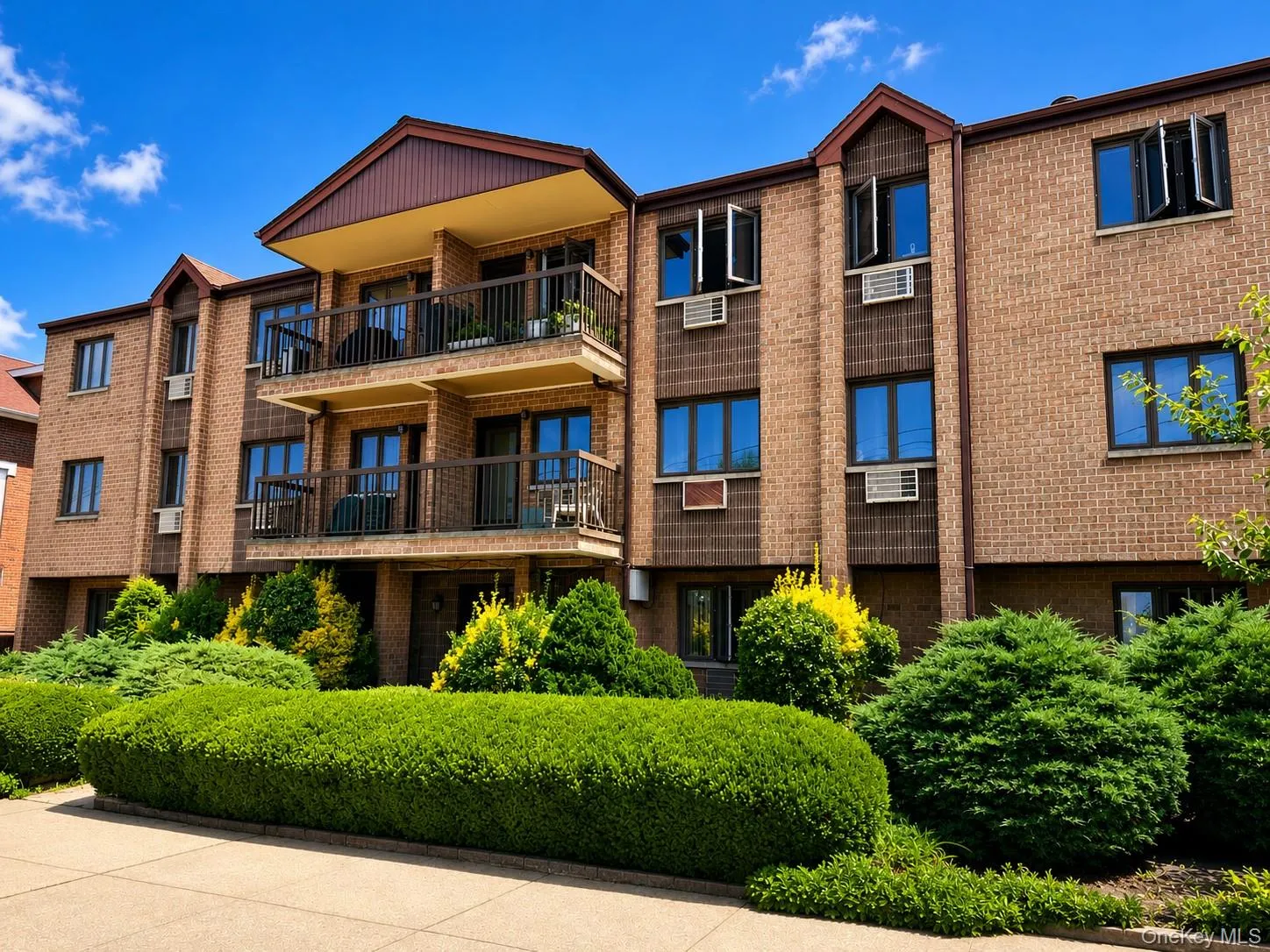 Multi-story brick building facade with dark-framed windows, individual balconies, and prominent window air conditioning units Multi-story brick building facade with dark-framed windows, individual balconies, and prominent window air conditioning units