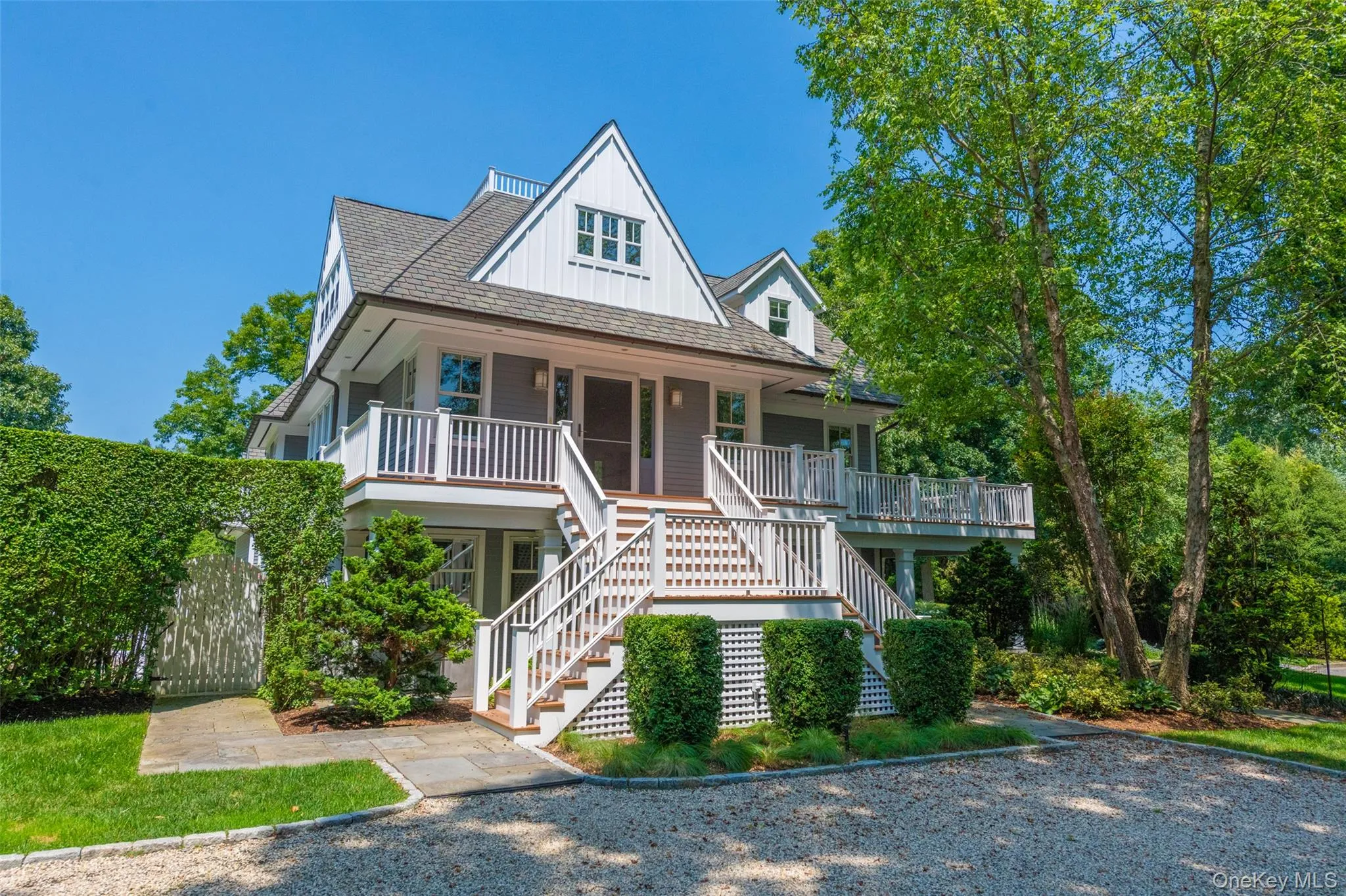 Shingle-style home featuring a prominent gabled roofline, multiple balconies, and a grand exterior staircase Shingle-style home featuring a prominent gabled roofline, multiple balconies, and a grand exterior staircase