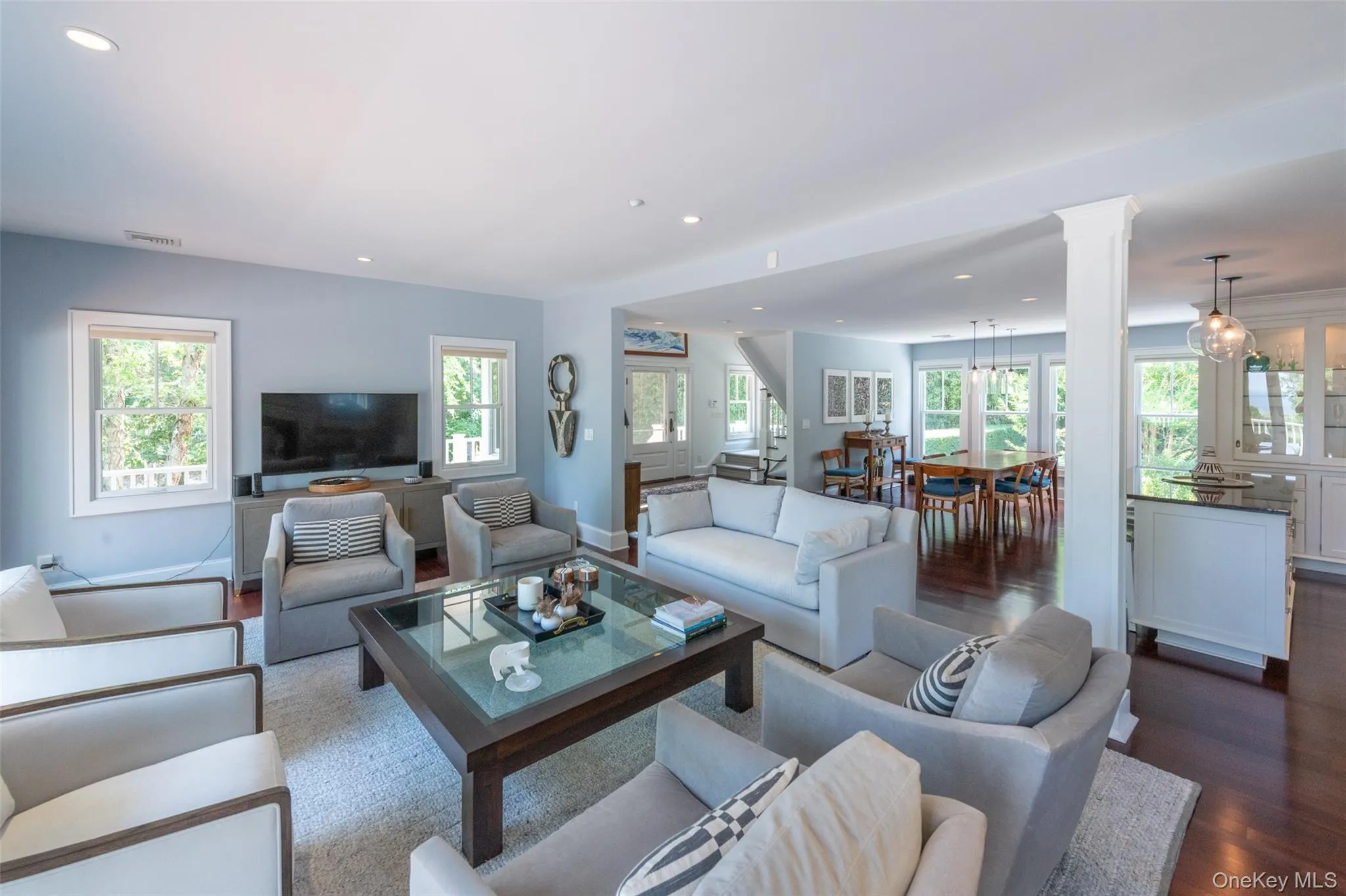 Open-concept living space featuring hardwood flooring, recessed lighting, and ample natural light from multiple windows Open-concept living space featuring hardwood flooring, recessed lighting, and ample natural light from multiple windows