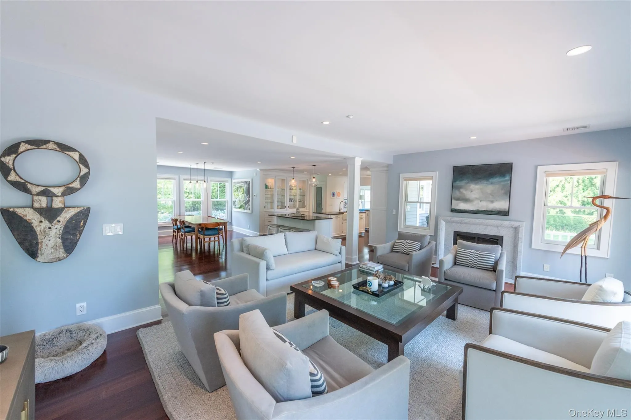 Spacious living room featuring recessed lighting, a stone-surround fireplace, rich wood-finish flooring, and multiple windows Spacious living room featuring recessed lighting, a stone-surround fireplace, rich wood-finish flooring, and multiple windows