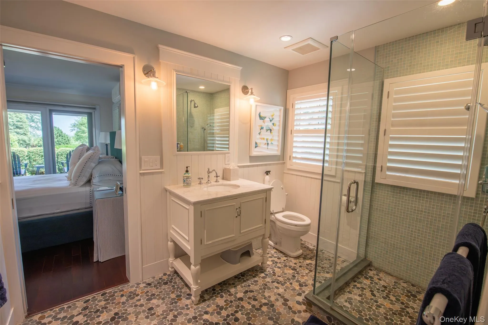 Bathroom featuring pebble tile flooring, a glass-enclosed shower with tiled walls, and a vanity with a stone countertop Bathroom featuring pebble tile flooring, a glass-enclosed shower with tiled walls, and a vanity with a stone countertop