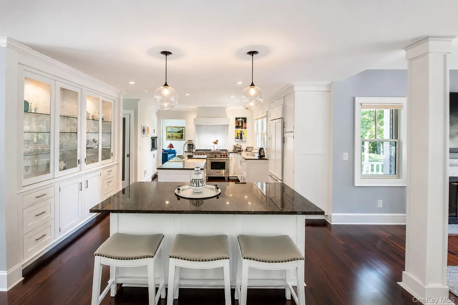 Kitchen featuring a central island with dark countertop, pendant lighting, and rich wood-finish flooring Kitchen featuring a central island with dark countertop, pendant lighting, and rich wood-finish flooring