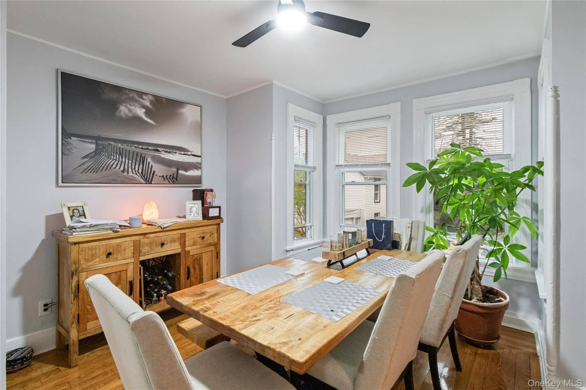 Dining area with hardwood flooring, a ceiling fan fixture, and multiple windows providing natural illumination Dining area with hardwood flooring, a ceiling fan fixture, and multiple windows providing natural illumination
