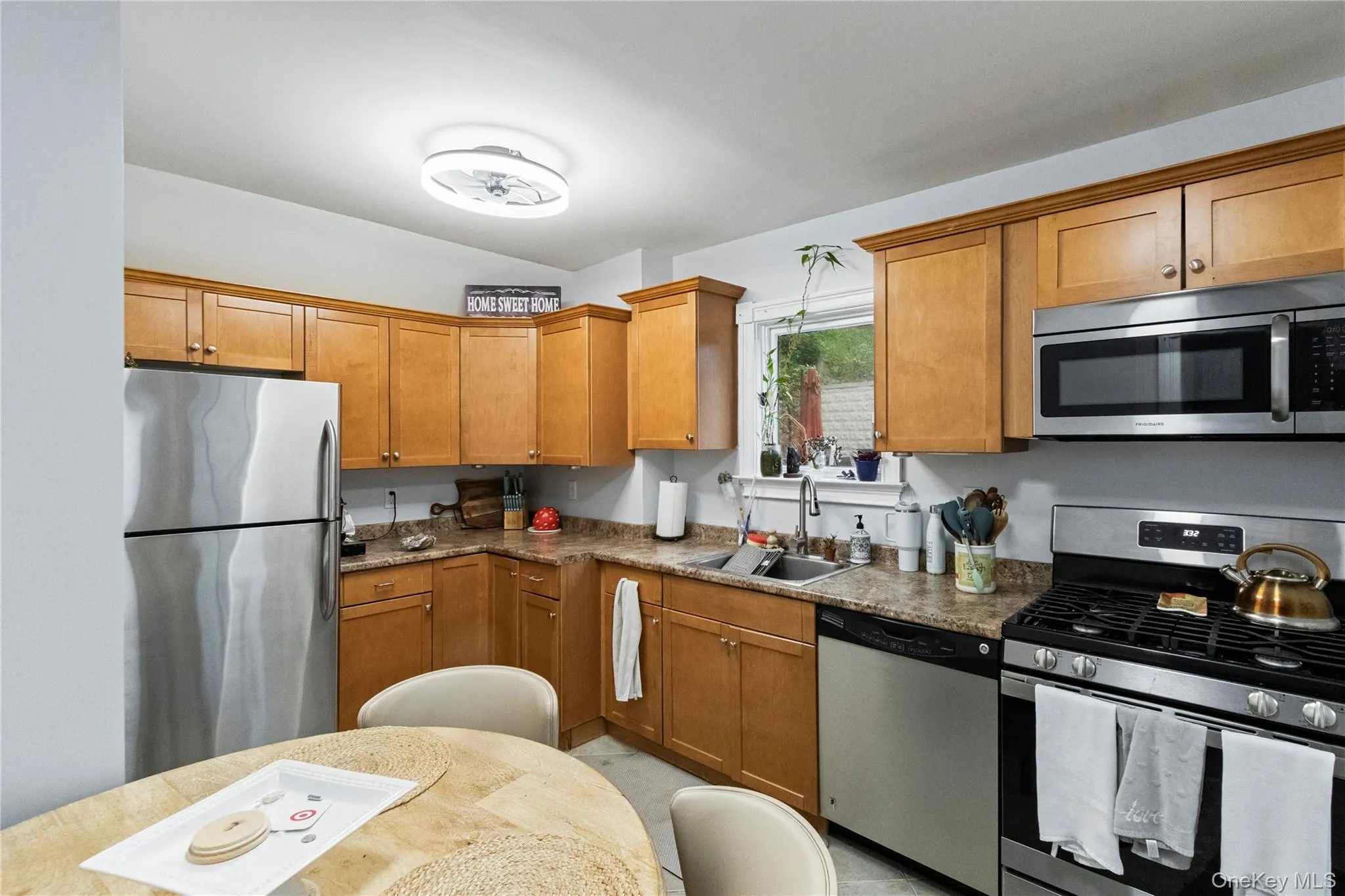 Kitchen featuring shaker-style cabinetry, stainless steel appliances, a double basin sink, and a multi-tone countertop Kitchen featuring shaker-style cabinetry, stainless steel appliances, a double basin sink, and a multi-tone countertop