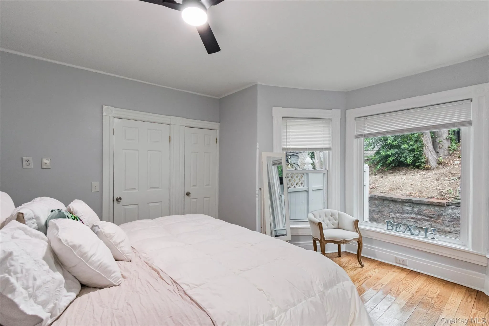 Corner window arrangement with natural light, wood-finish flooring, and a ceiling fan with integrated lighting Corner window arrangement with natural light, wood-finish flooring, and a ceiling fan with integrated lighting