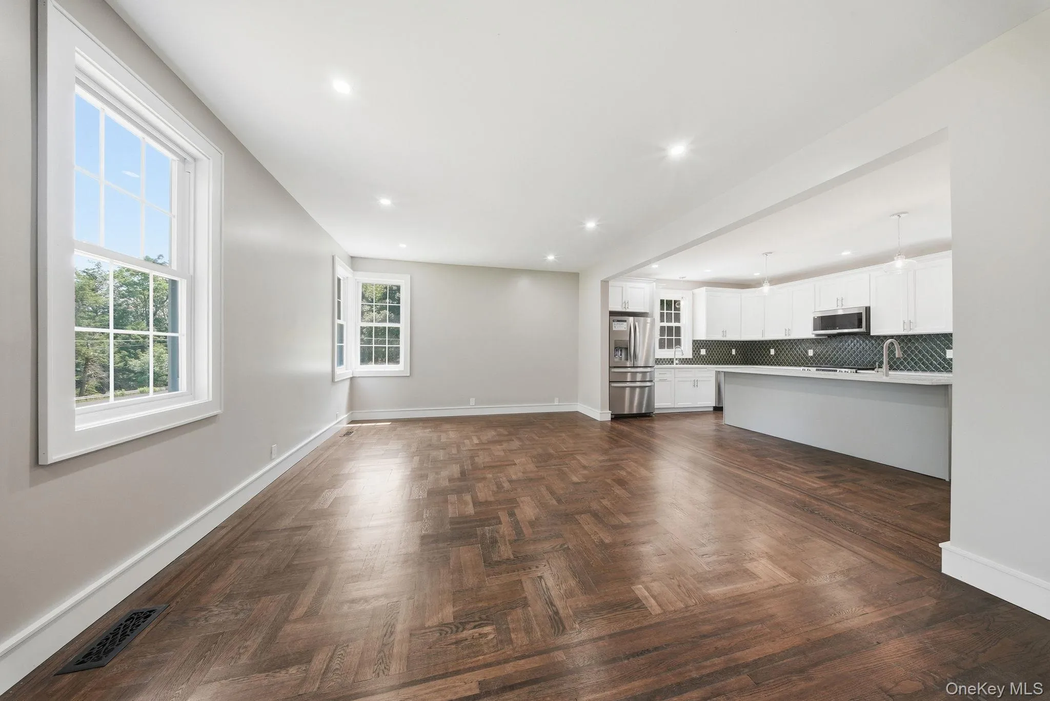 Spacious interior featuring wood-finish herringbone flooring, recessed lighting, and large windows Spacious interior featuring wood-finish herringbone flooring, recessed lighting, and large windows