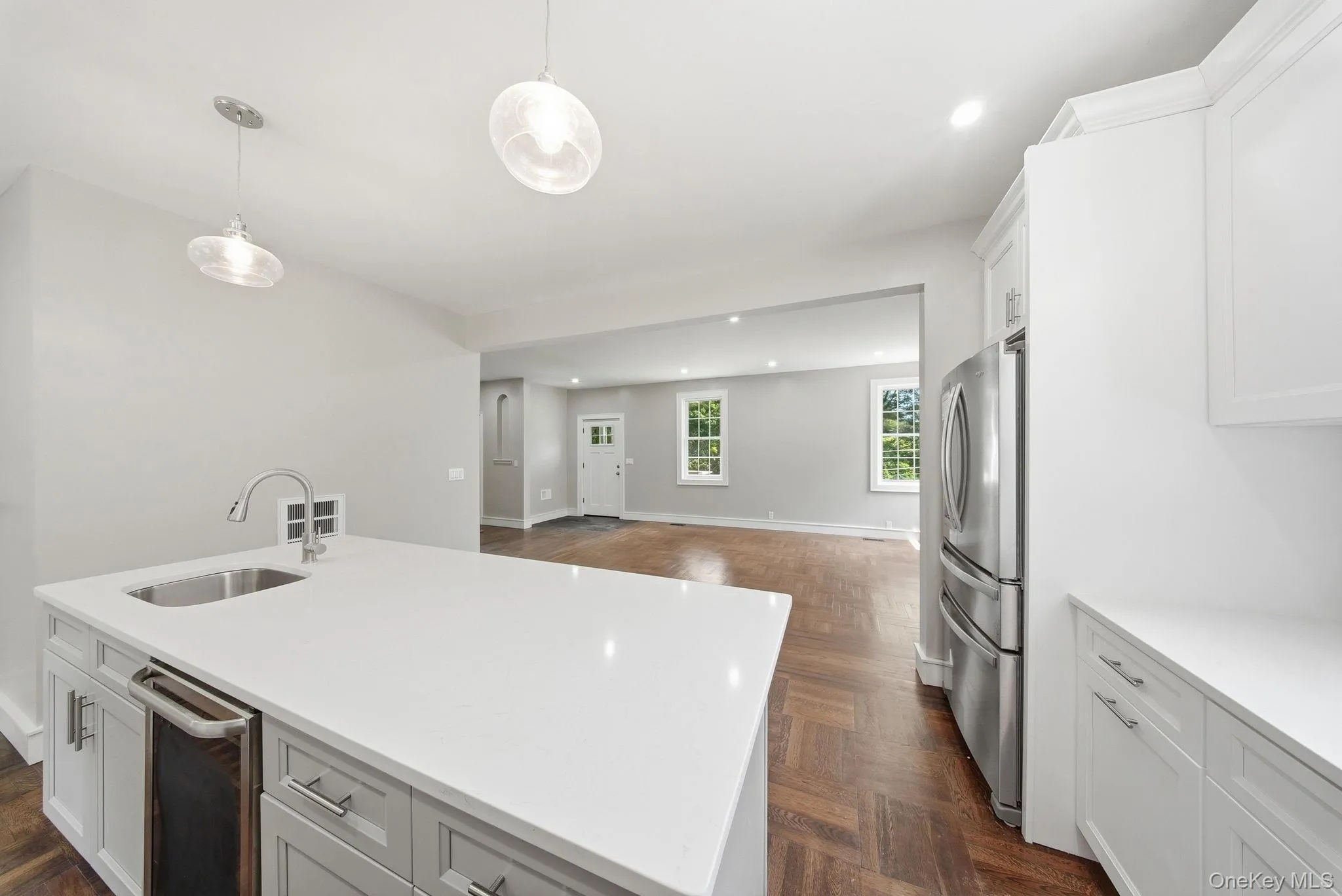Kitchen island featuring a stainless steel sink with gooseneck faucet, an integrated beverage cooler, and white countertop Kitchen island featuring a stainless steel sink with gooseneck faucet, an integrated beverage cooler, and white countertop