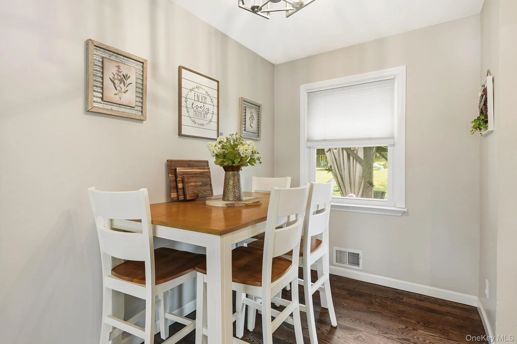 Dining area featuring a single window with white trim, dark wood-finish flooring, and light-toned walls Dining area featuring a single window with white trim, dark wood-finish flooring, and light-toned walls