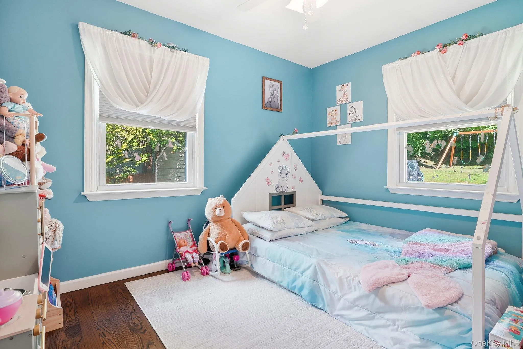 Bright room featuring two large windows, white trim, and wood-finish flooring Bright room featuring two large windows, white trim, and wood-finish flooring