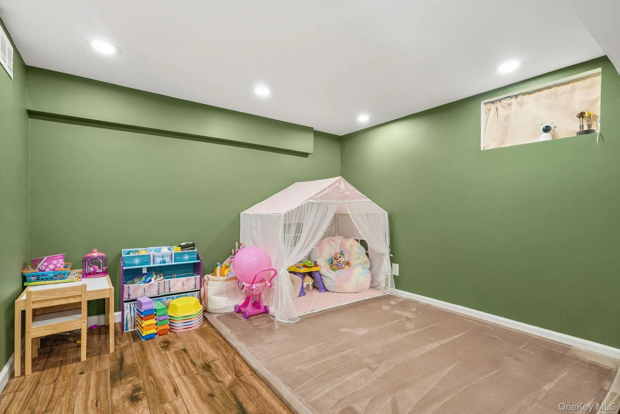 Finished room featuring recessed lighting, a window opening, and a combination of wood-finish flooring Finished room featuring recessed lighting, a window opening, and a combination of wood-finish flooring