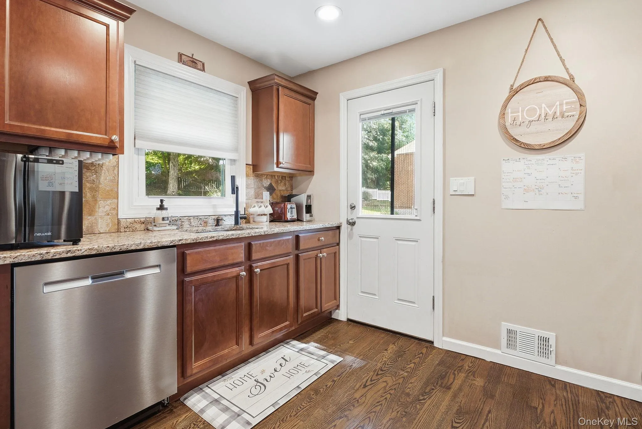Kitchen featuring wood-finish flooring, cherry wood cabinetry, light-toned granite countertops, and a full-light exterior door Kitchen featuring wood-finish flooring, cherry wood cabinetry, light-toned granite countertops, and a full-light exterior door