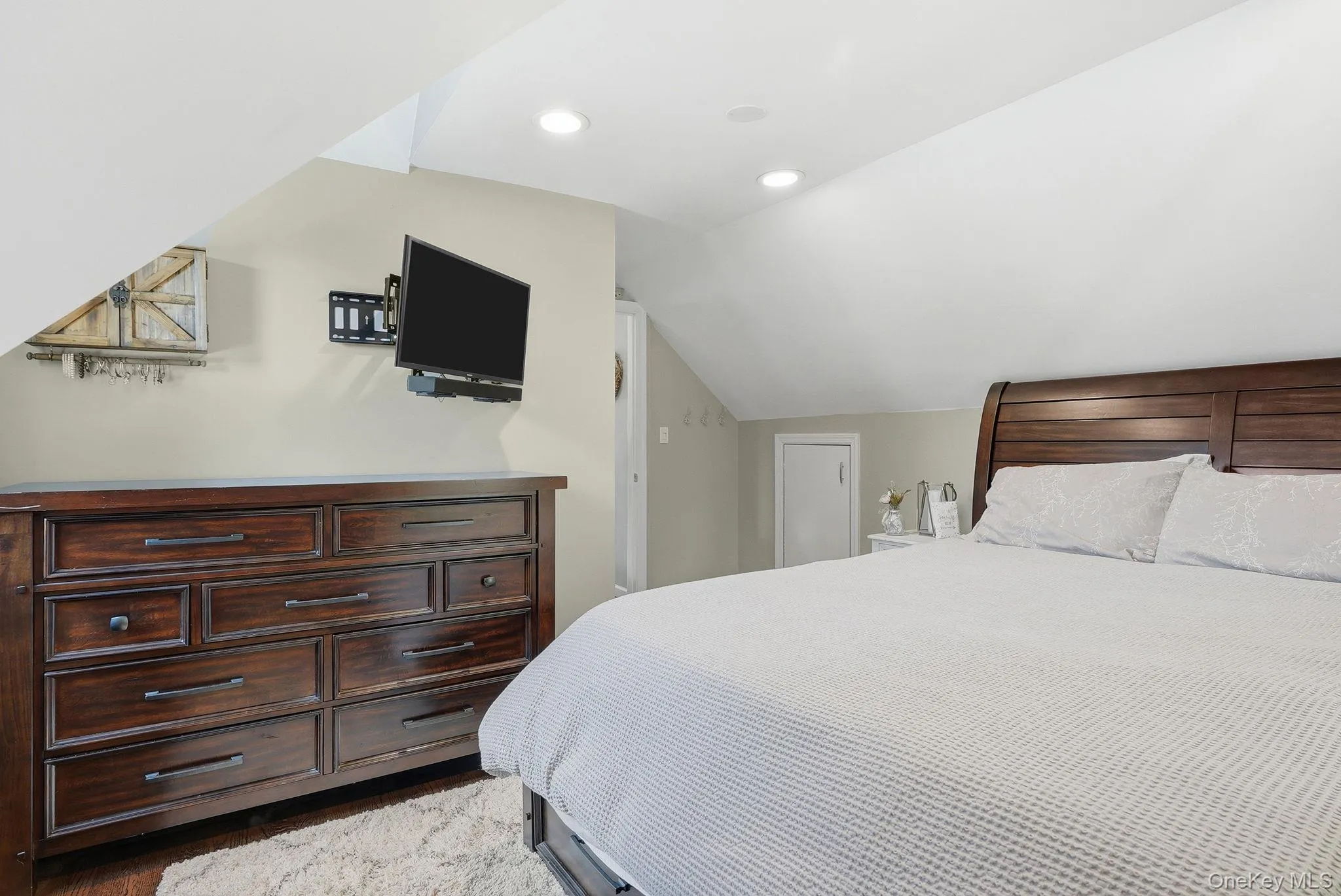 Spacious room featuring wood-finish flooring, recessed lighting, and an angled ceiling Spacious room featuring wood-finish flooring, recessed lighting, and an angled ceiling