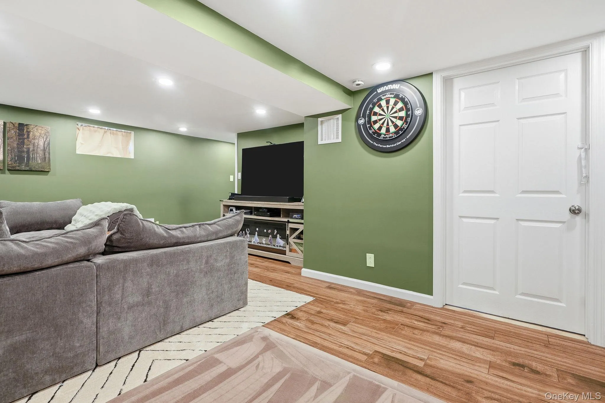 Recreation room featuring wood-finish flooring, recessed lighting, and a neutral color palette Recreation room featuring wood-finish flooring, recessed lighting, and a neutral color palette