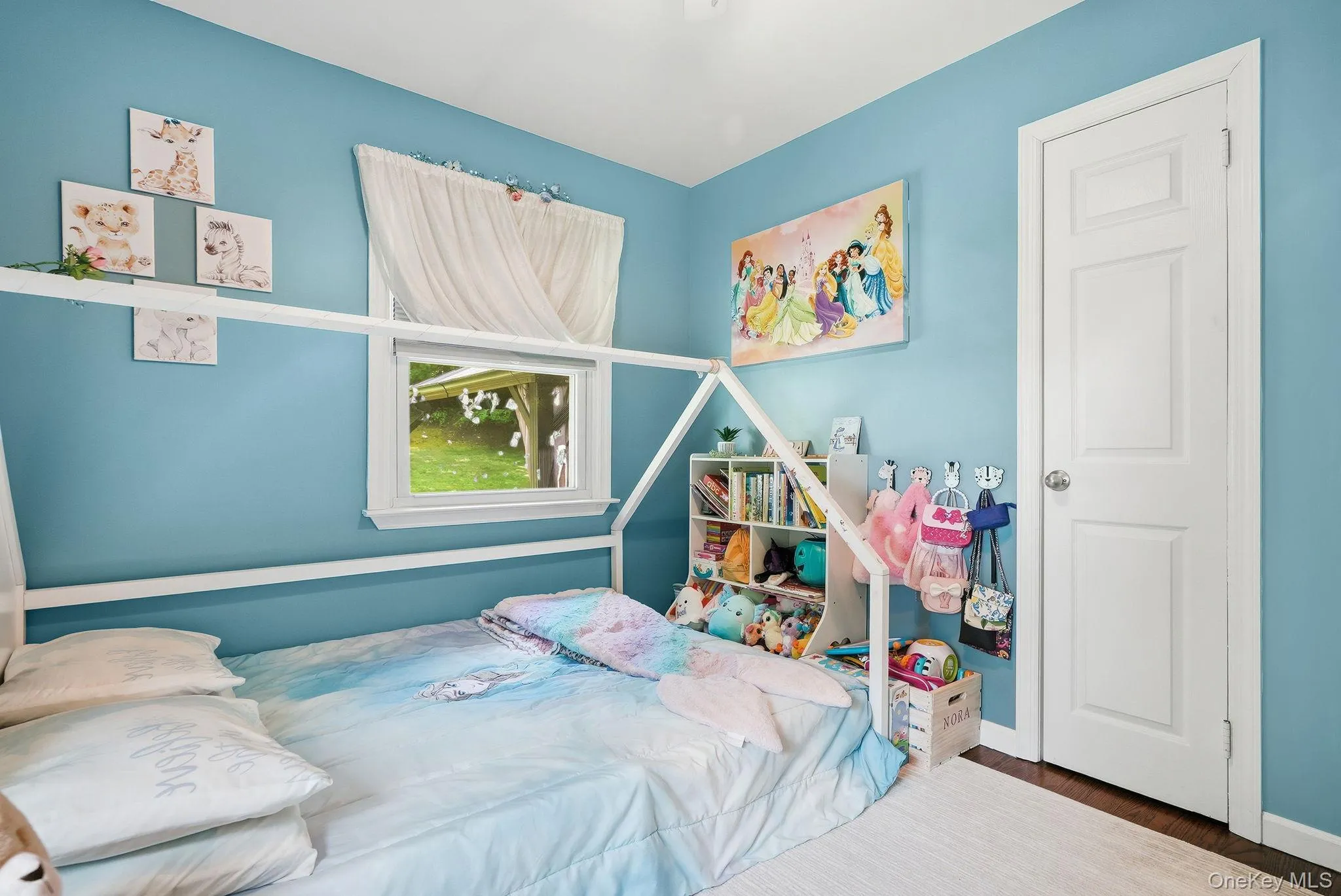 Bedroom featuring a single window with white trim, a white paneled door, and wood-finish flooring Bedroom featuring a single window with white trim, a white paneled door, and wood-finish flooring