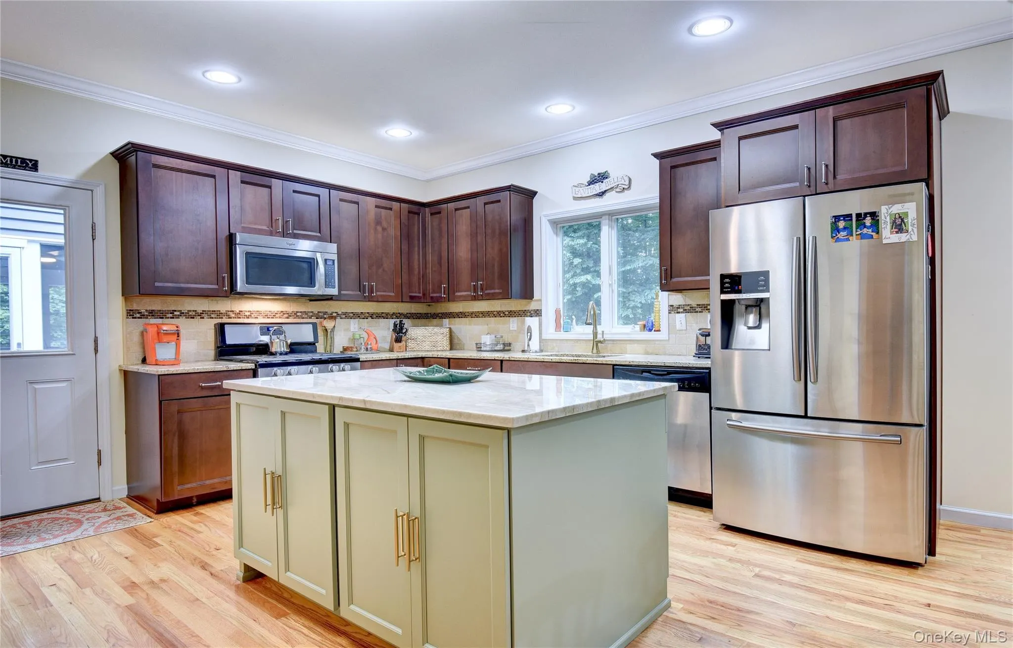 Legal accessory apartment: Kitchen featuring wood flooring, a central island with quartz countertop, dark wood upper and lower cabinetry, stainless steel appliances, and recessed lighting Legal accessory apartment: Kitchen featuring wood flooring, a central island with quartz countertop, dark wood upper and lower cabinetry, stainless steel appliances, and recessed lighting