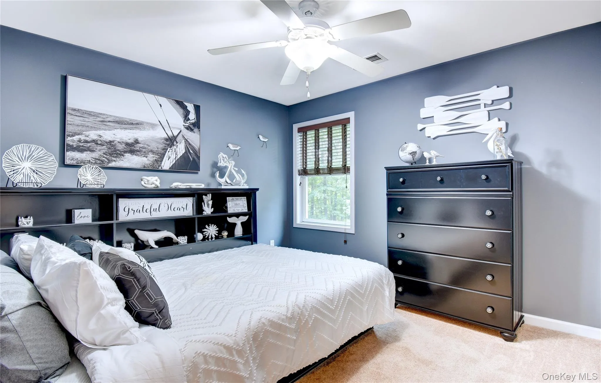 Carpeted bedroom featuring a ceiling fan with integrated lighting, and a window with blinds Carpeted bedroom featuring a ceiling fan with integrated lighting, and a window with blinds