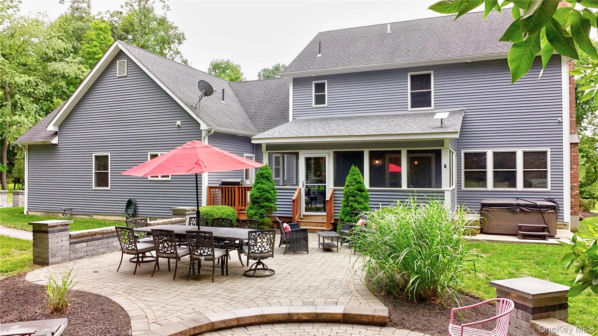 Expansive paver patio with a stone wall, offering direct access to the screened porch and a dedicated space for outdoor entertaining Expansive paver patio with a stone wall, offering direct access to the screened porch and a dedicated space for outdoor entertaining