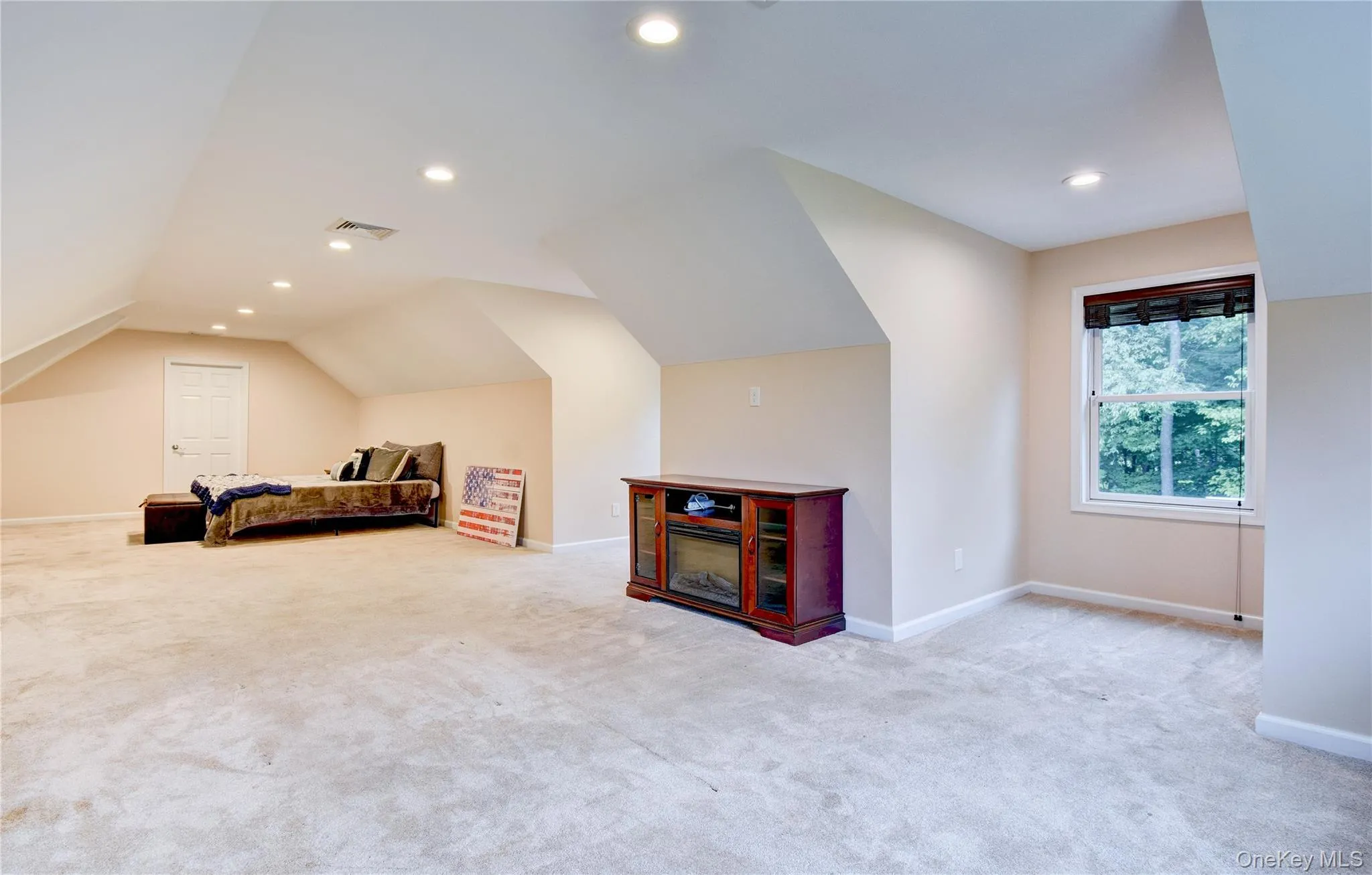 Spacious bonus room featuring vaulted ceilings, recessed lighting, neutral wall tones, light-colored carpeting, and a window with exterior tree views Spacious bonus room featuring vaulted ceilings, recessed lighting, neutral wall tones, light-colored carpeting, and a window with exterior tree views
