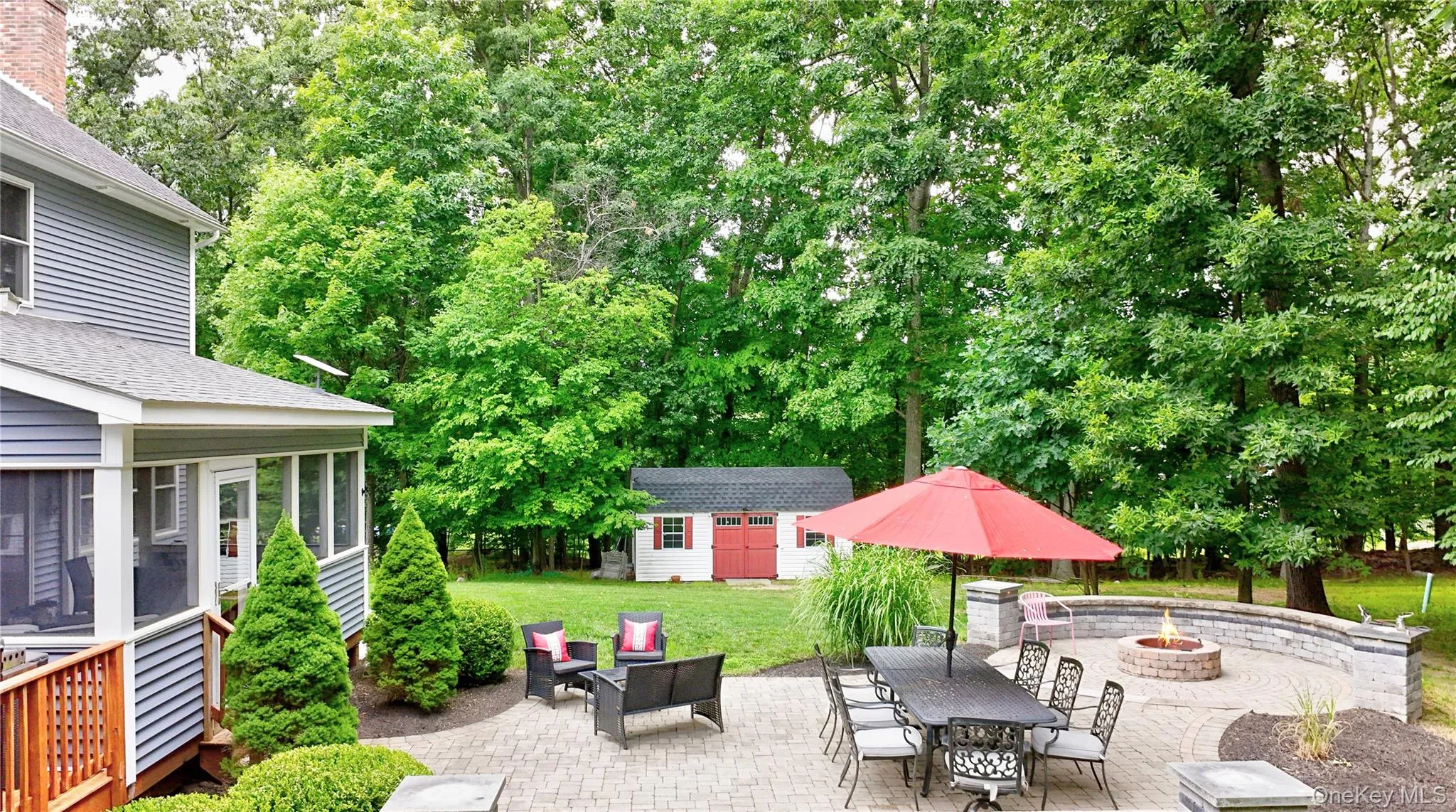 Expansive paver patio with a built-in fire pit and a stone retaining wall Expansive paver patio with a built-in fire pit and a stone retaining wall