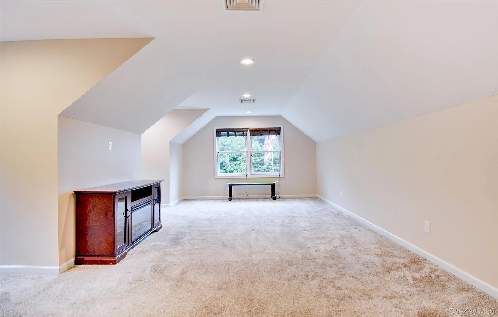 Spacious bonus room featuring sloped ceilings, recessed lighting, a window with exterior visibility, and light-toned carpeting Spacious bonus room featuring sloped ceilings, recessed lighting, a window with exterior visibility, and light-toned carpeting
