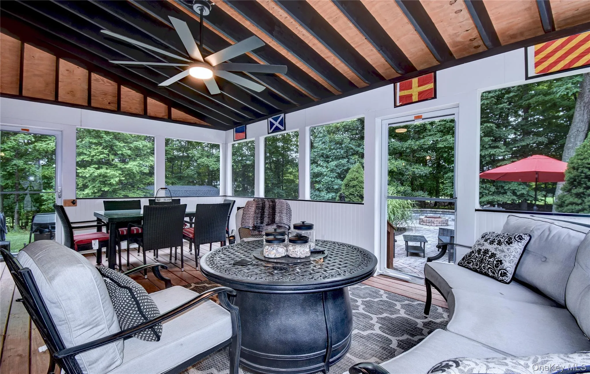 Screened porch featuring a vaulted ceiling with exposed beams, wood-finish flooring, and a ceiling fan Screened porch featuring a vaulted ceiling with exposed beams, wood-finish flooring, and a ceiling fan