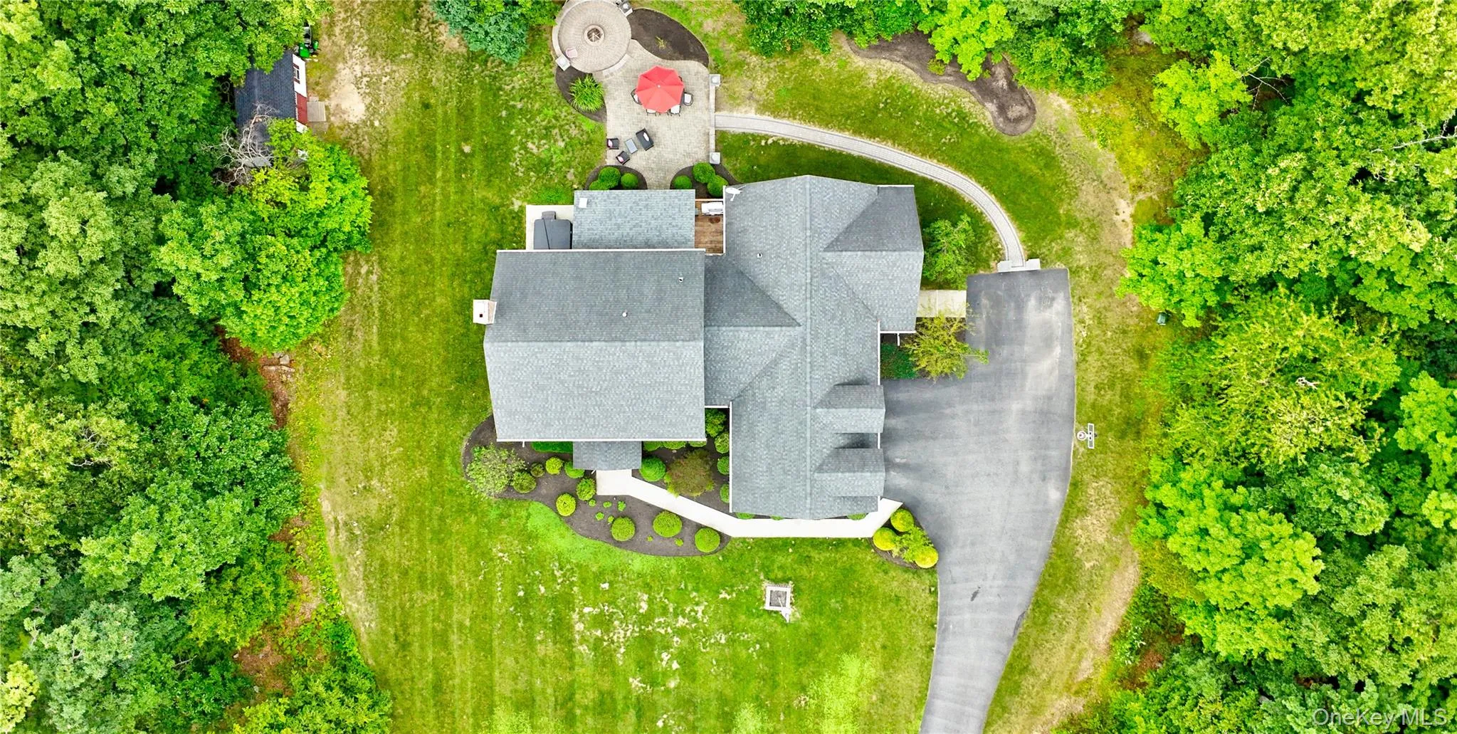Expansive property featuring a multi-gabled roofline, a paved driveway, and a stone patio Expansive property featuring a multi-gabled roofline, a paved driveway, and a stone patio