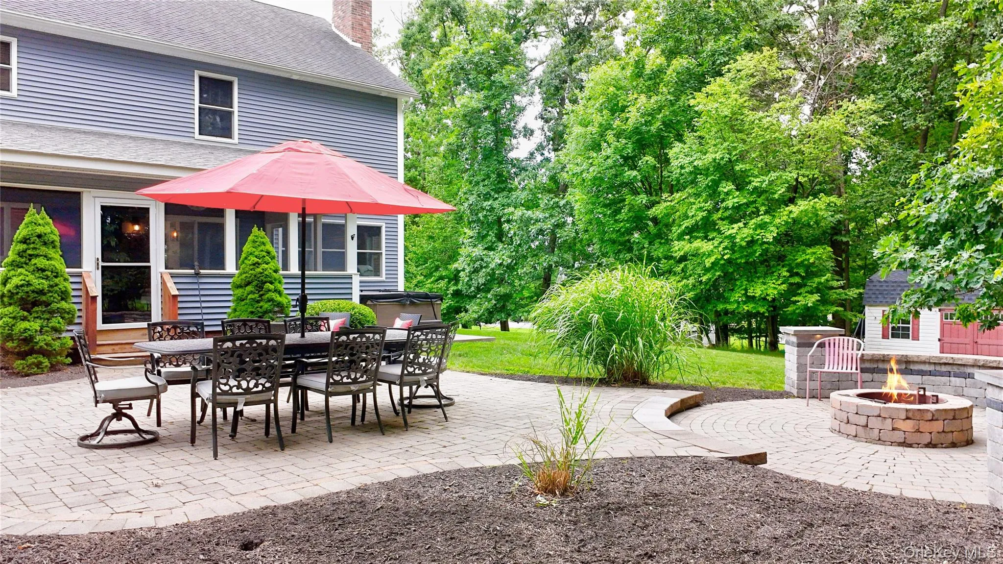 Expansive paver patio featuring a built-in fire pit, multiple seating areas, and direct access to the home Expansive paver patio featuring a built-in fire pit, multiple seating areas, and direct access to the home