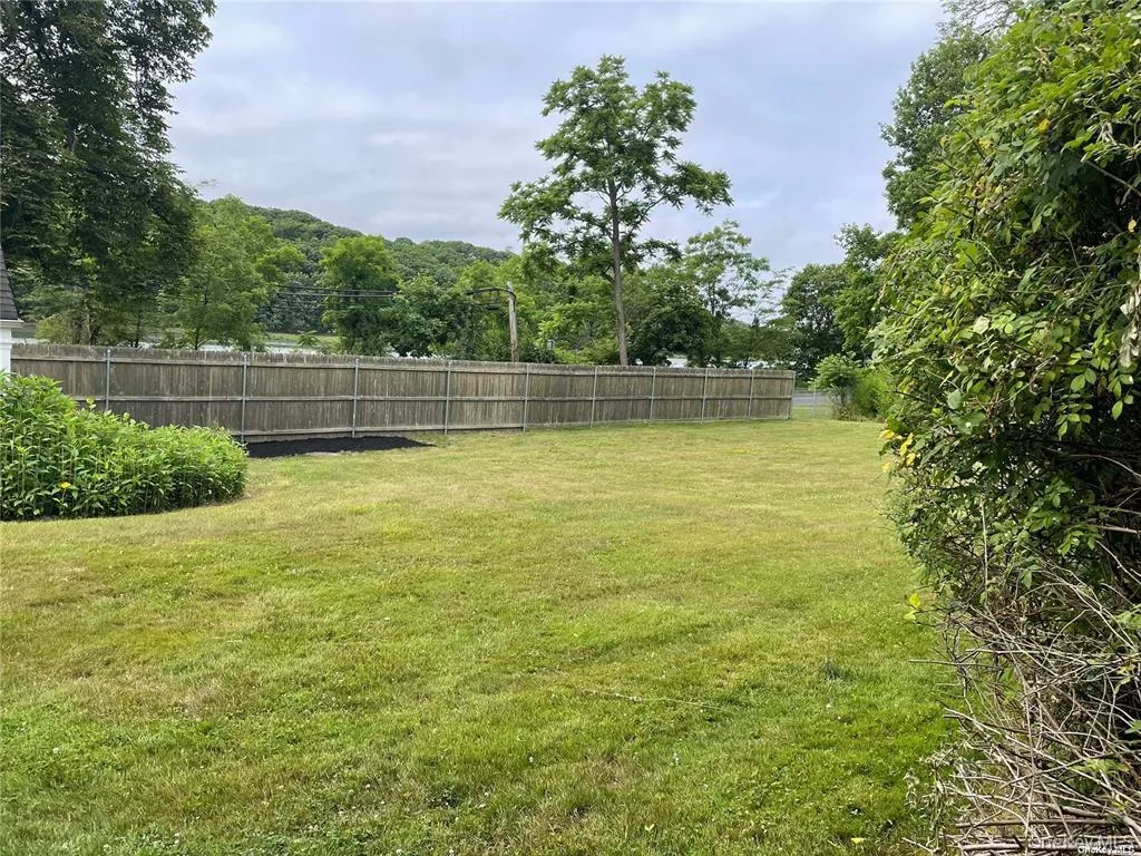 Spacious backyard featuring a manicured lawn, a full wood privacy fence, and mature perimeter foliage Spacious backyard featuring a manicured lawn, a full wood privacy fence, and mature perimeter foliage
