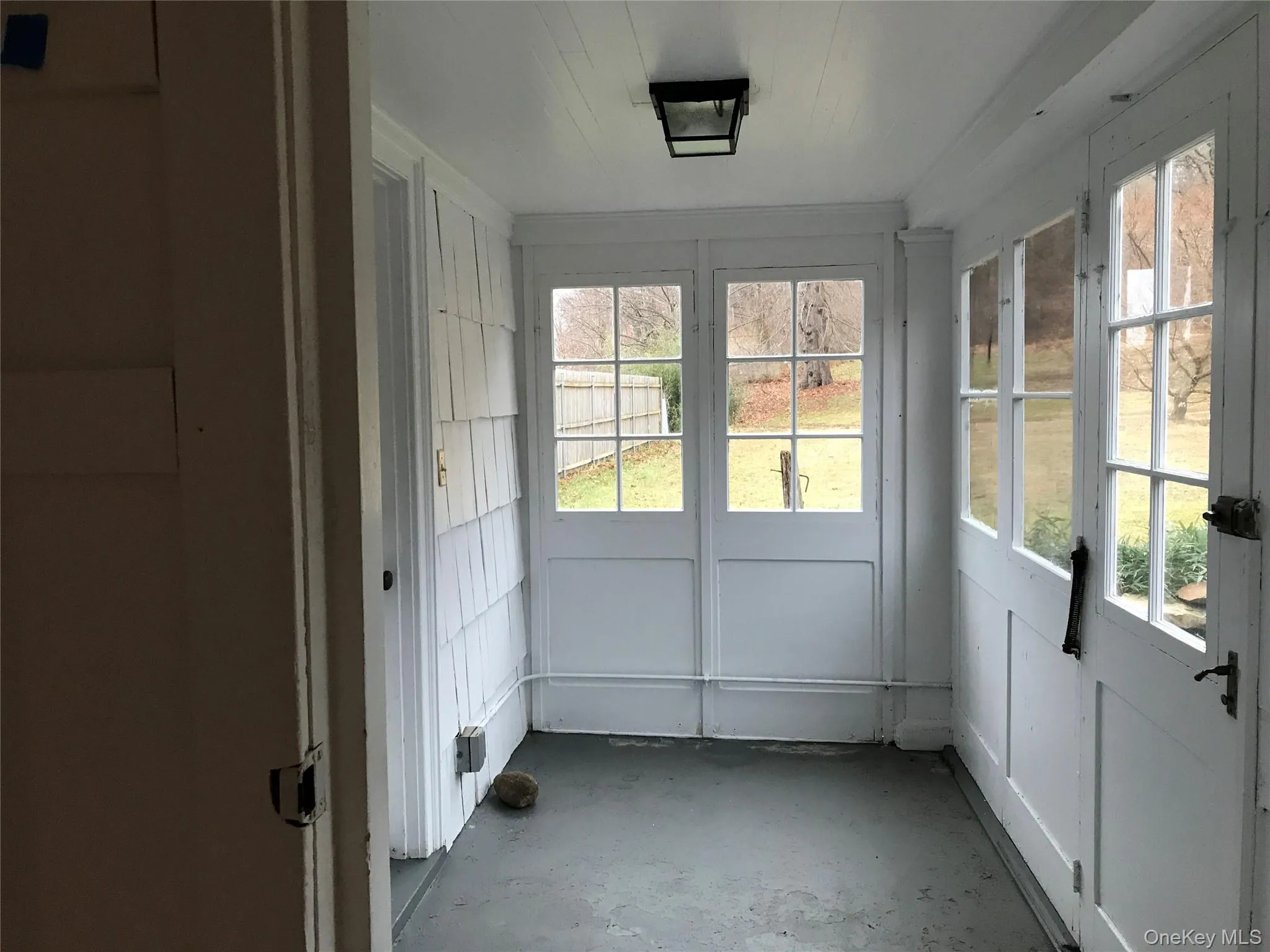 Enclosed porch with multiple paneled windows, shiplap wall accents, and an overhead flush-mount light fixture Enclosed porch with multiple paneled windows, shiplap wall accents, and an overhead flush-mount light fixture