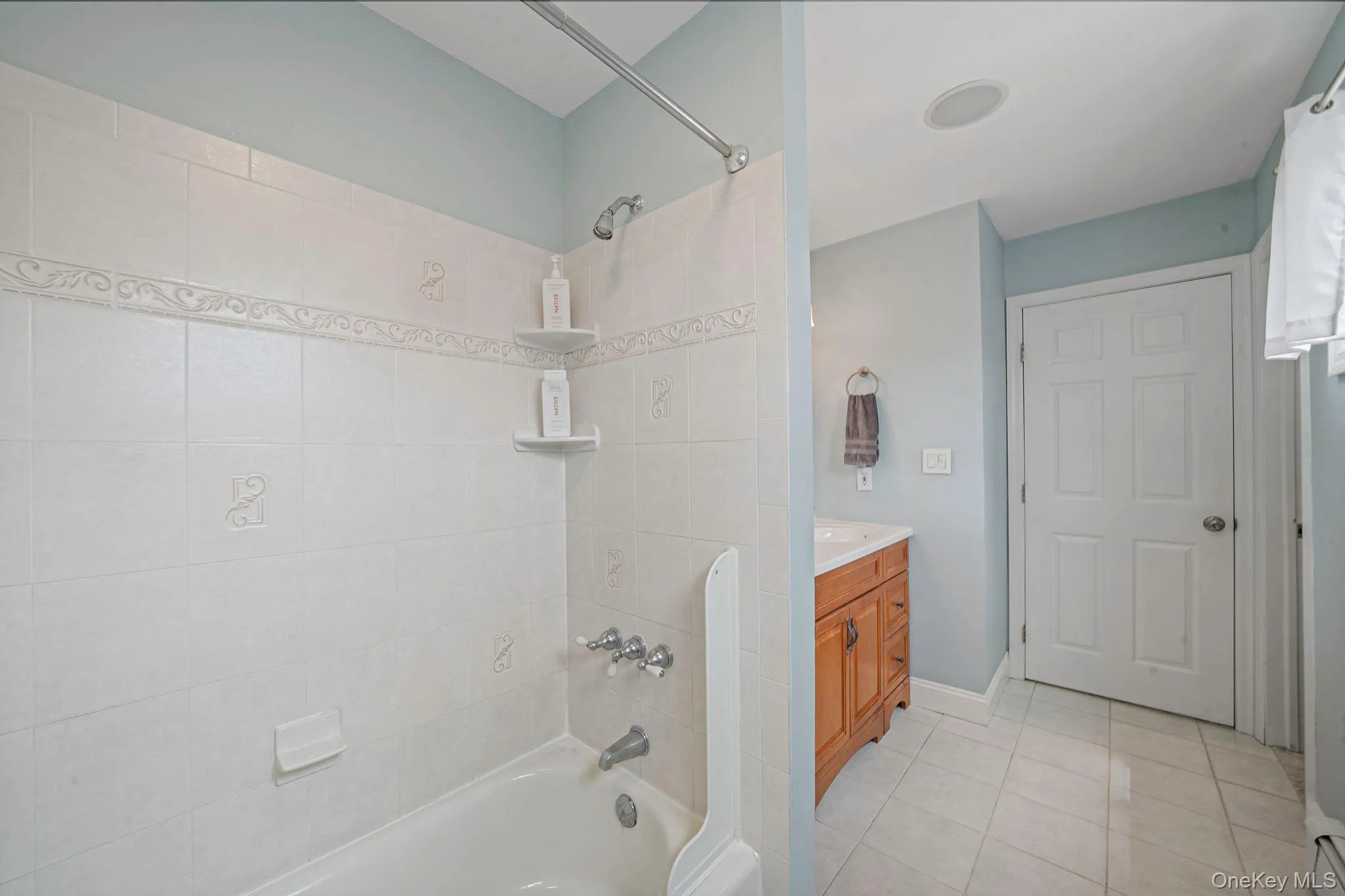 Light and bright white tiled surround tub/shower combination. Light and bright white tiled surround tub/shower combination.