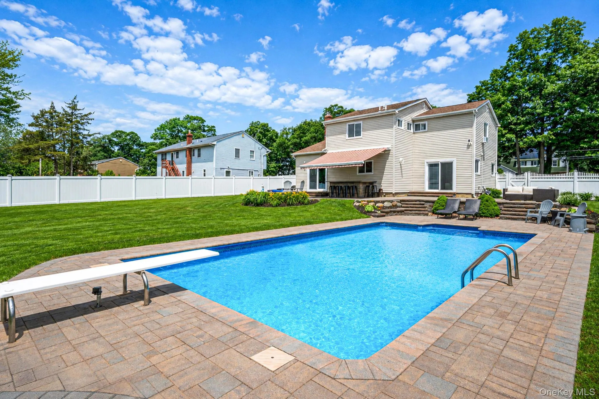 Expansive backyard featuring 18 x 36 rectangular swimming pool with a diving board and entry handrails, surrounded by Cambridge paver patio surfacing. Professional landscaping & in-ground sprinklers Expansive backyard featuring 18 x 36 rectangular swimming pool with a diving board and entry handrails, surrounded by Cambridge paver patio surfacing. Professional landscaping & in-ground sprinklers