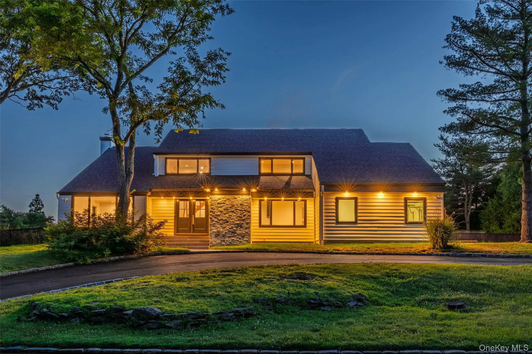 Contemporary-style residence featuring a dark shingle roof and a combination of horizontal siding and stone veneer on the facade Contemporary-style residence featuring a dark shingle roof and a combination of horizontal siding and stone veneer on the facade