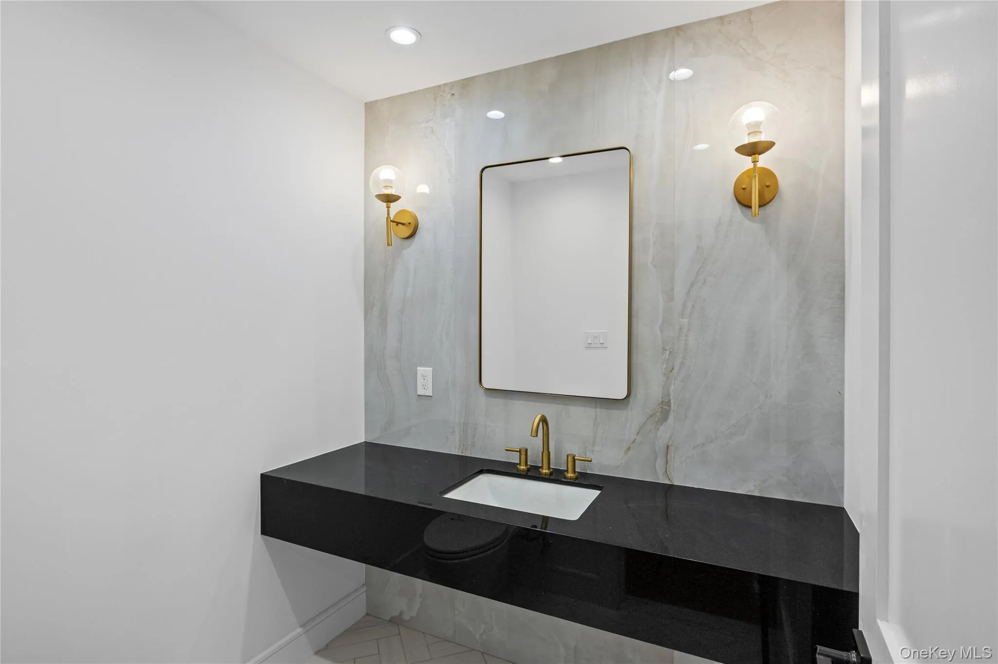 Floating vanity with a polished black countertop and integrated rectangular sink. Foyer entryway half bathroom. Floating vanity with a polished black countertop and integrated rectangular sink. Foyer entryway half bathroom.