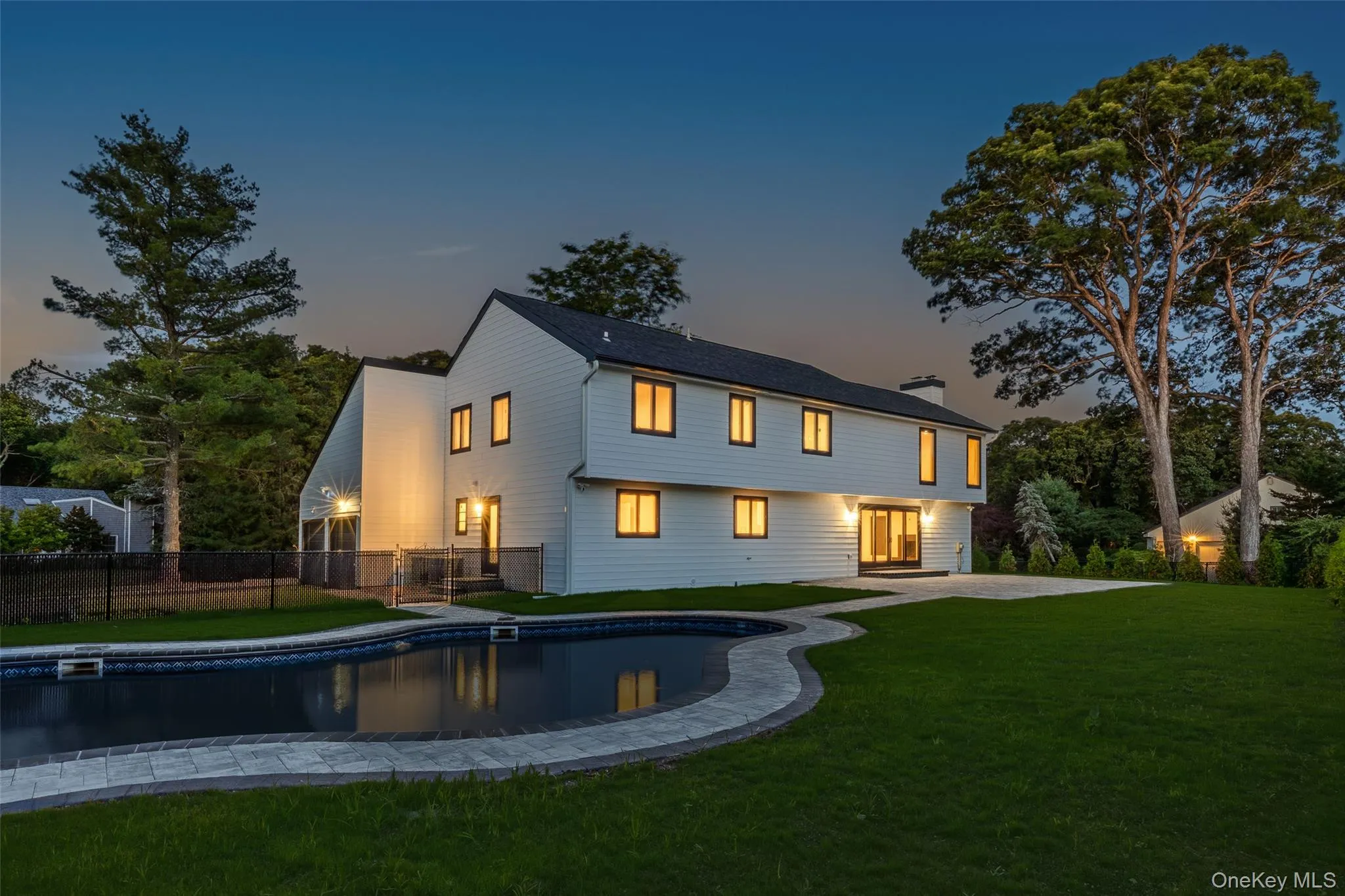 Expansive rear yard featuring a swimming pool with a paved surround, a spacious patio area, and a manicured lawn Expansive rear yard featuring a swimming pool with a paved surround, a spacious patio area, and a manicured lawn