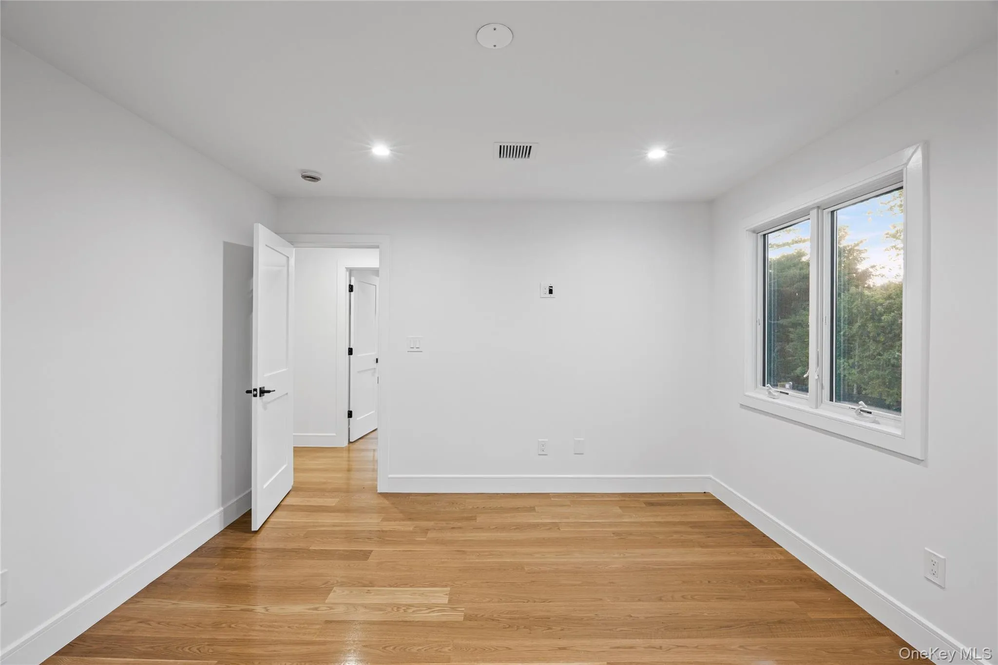 Bright interior space featuring light wood-finish flooring, recessed lighting, and white walls Bright interior space featuring light wood-finish flooring, recessed lighting, and white walls