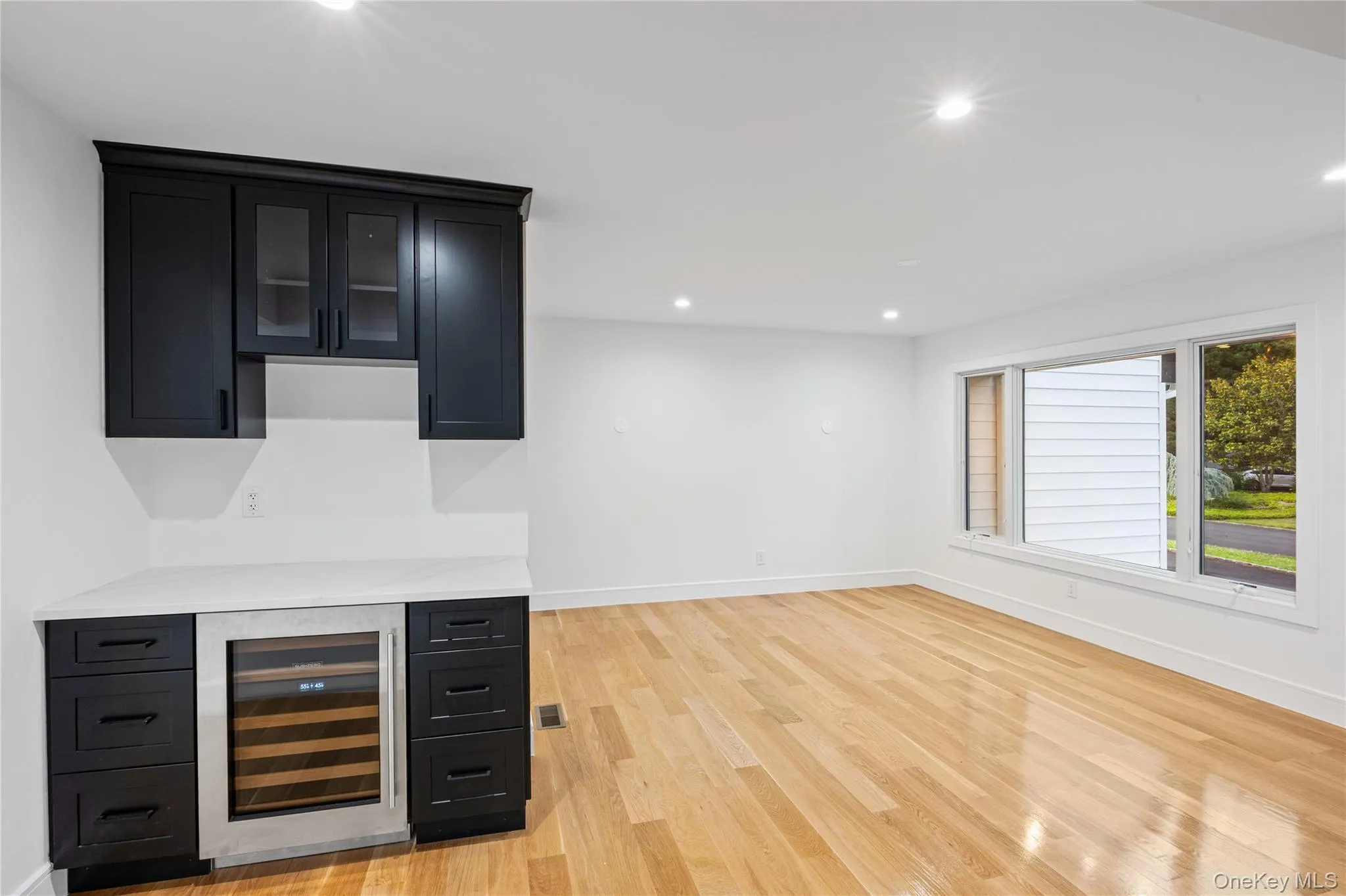 Built-in wet bar featuring dark cabinetry, a beverage refrigerator, and a light-colored countertop Built-in wet bar featuring dark cabinetry, a beverage refrigerator, and a light-colored countertop