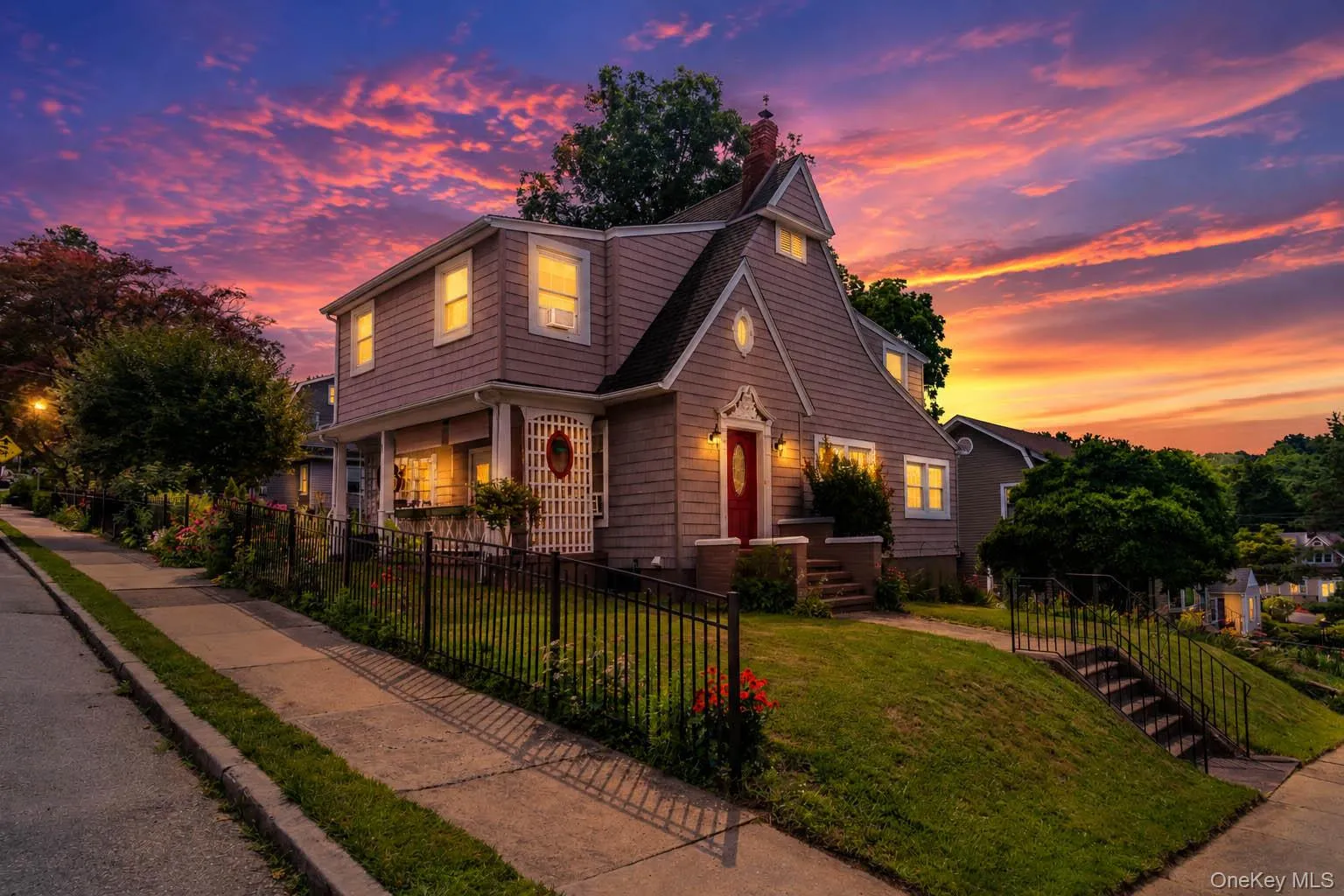 Shingle-sided residence with a prominent gable roofline and a vibrant red entry door Shingle-sided residence with a prominent gable roofline and a vibrant red entry door