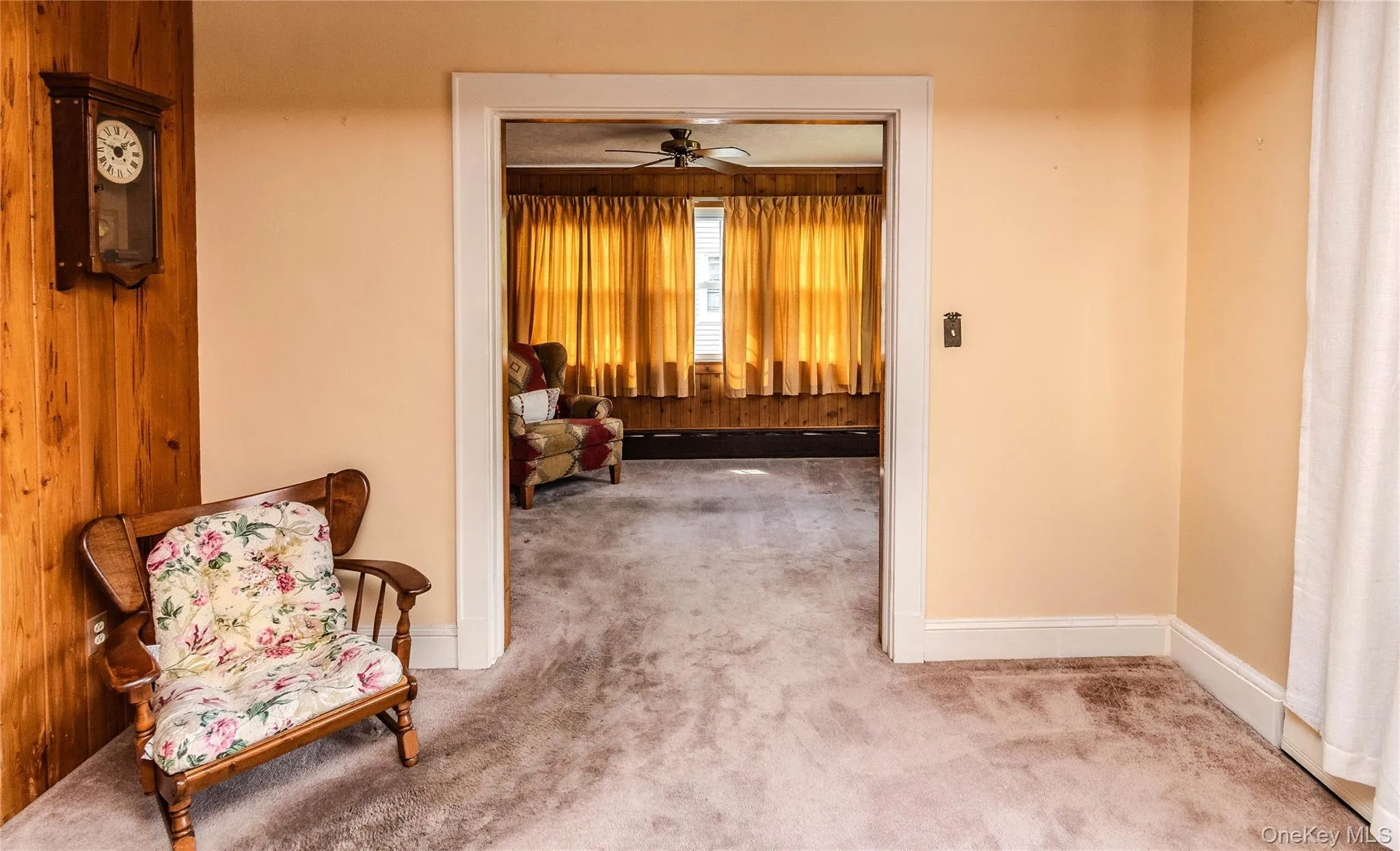 Carpeted interior space with a wood-paneled accent wall and light-toned painted walls Carpeted interior space with a wood-paneled accent wall and light-toned painted walls