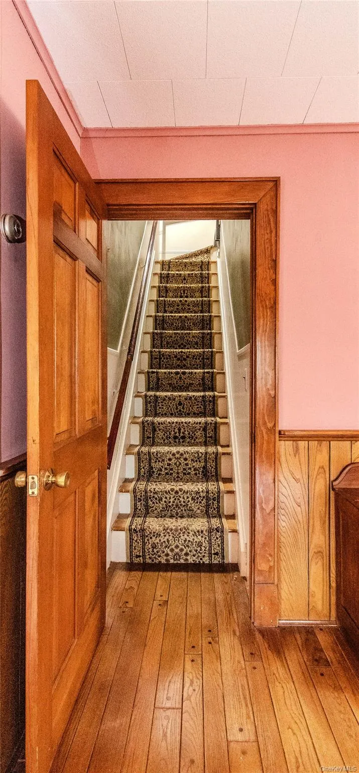 Hardwood flooring extending to a stairwell featuring a patterned runner Hardwood flooring extending to a stairwell featuring a patterned runner