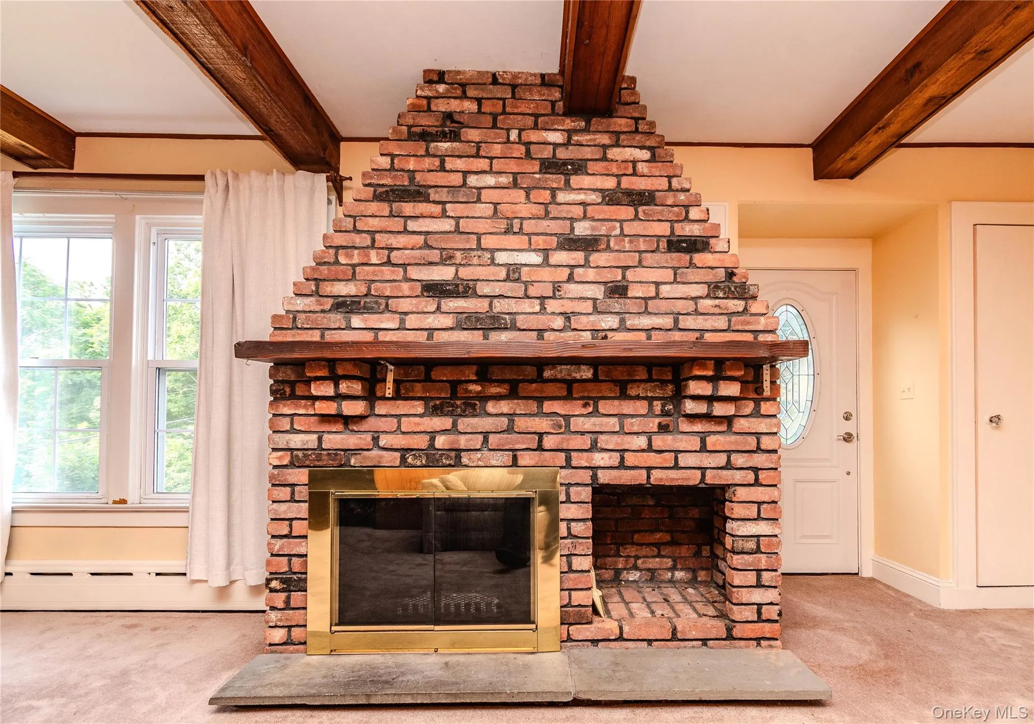 Brick fireplace with a brass firebox, wood mantel, and stone hearth Brick fireplace with a brass firebox, wood mantel, and stone hearth