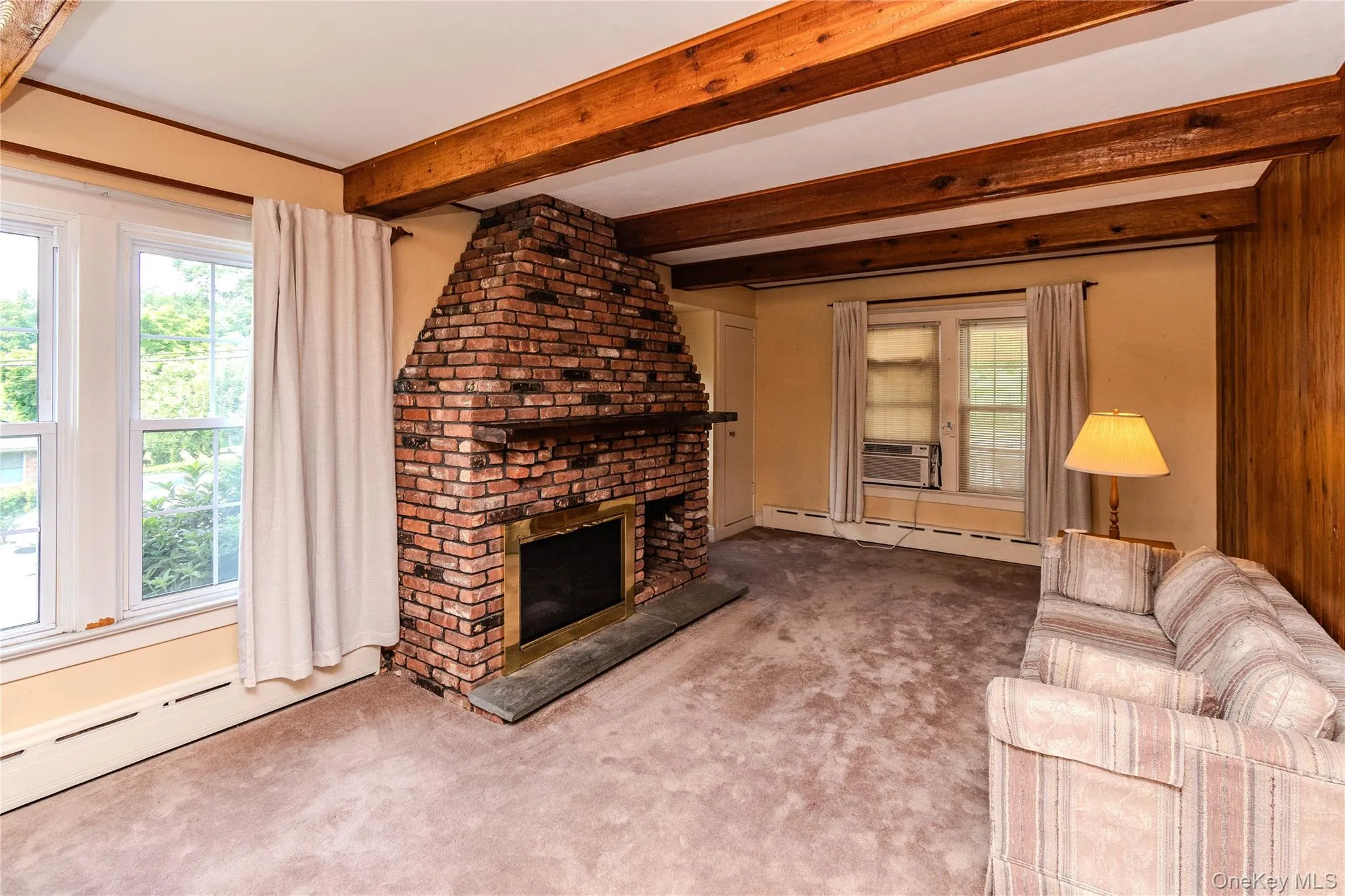 Exposed wood ceiling beams accenting a brick fireplace with a brass-trimmed firebox Exposed wood ceiling beams accenting a brick fireplace with a brass-trimmed firebox