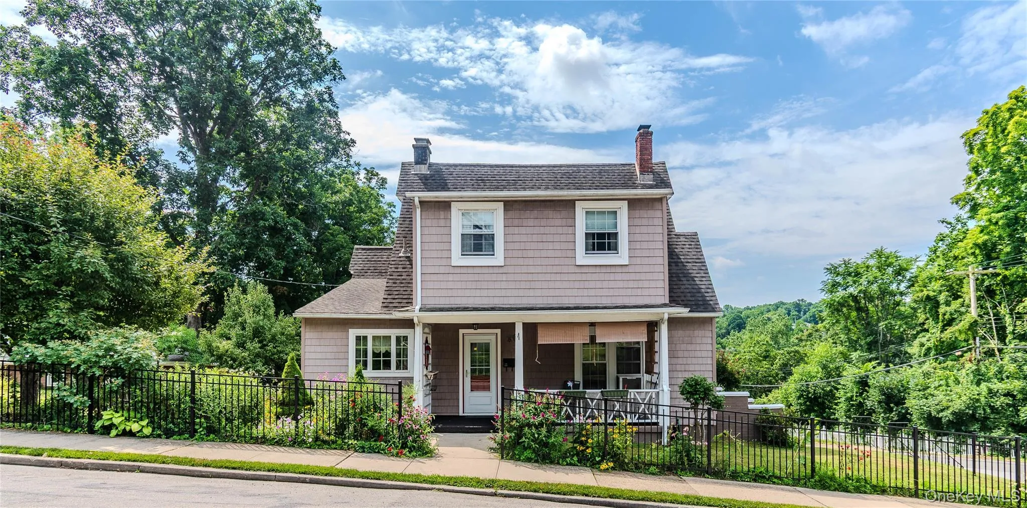 Traditional two-story residence featuring light-colored siding and a covered front porch Traditional two-story residence featuring light-colored siding and a covered front porch