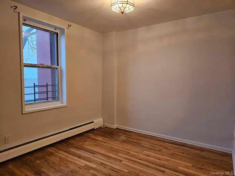 Spare room with baseboard heating and wood finished floors Spare room with baseboard heating and wood finished floors