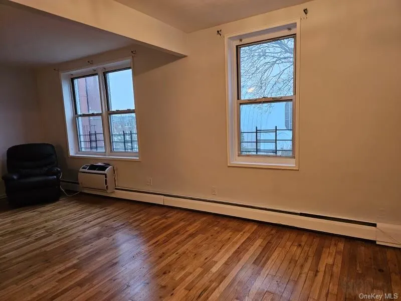Spare room featuring baseboard heating and hardwood / wood-style flooring Spare room featuring baseboard heating and hardwood / wood-style flooring