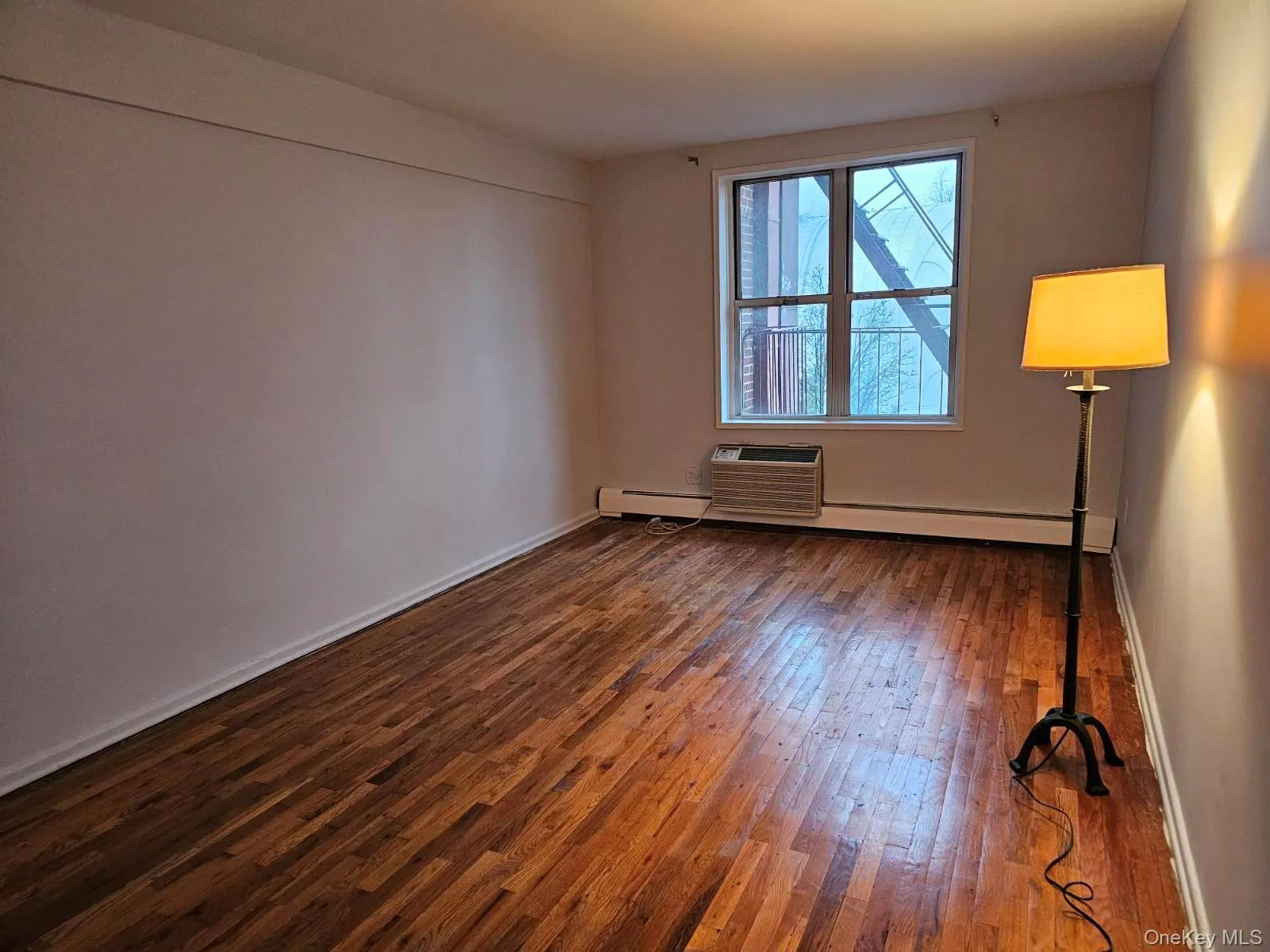 Empty room featuring dark wood-style floors and baseboard heating Empty room featuring dark wood-style floors and baseboard heating