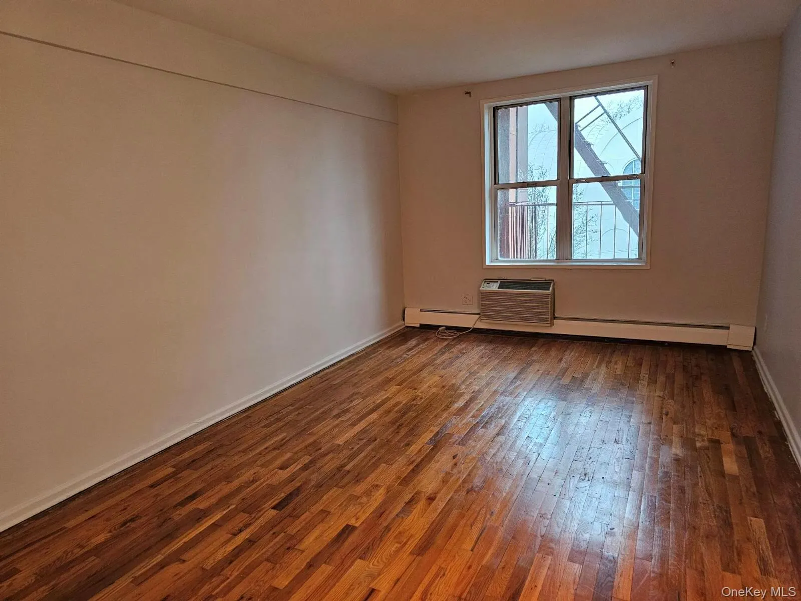 Spare room with dark wood-style floors and baseboard heating Spare room with dark wood-style floors and baseboard heating