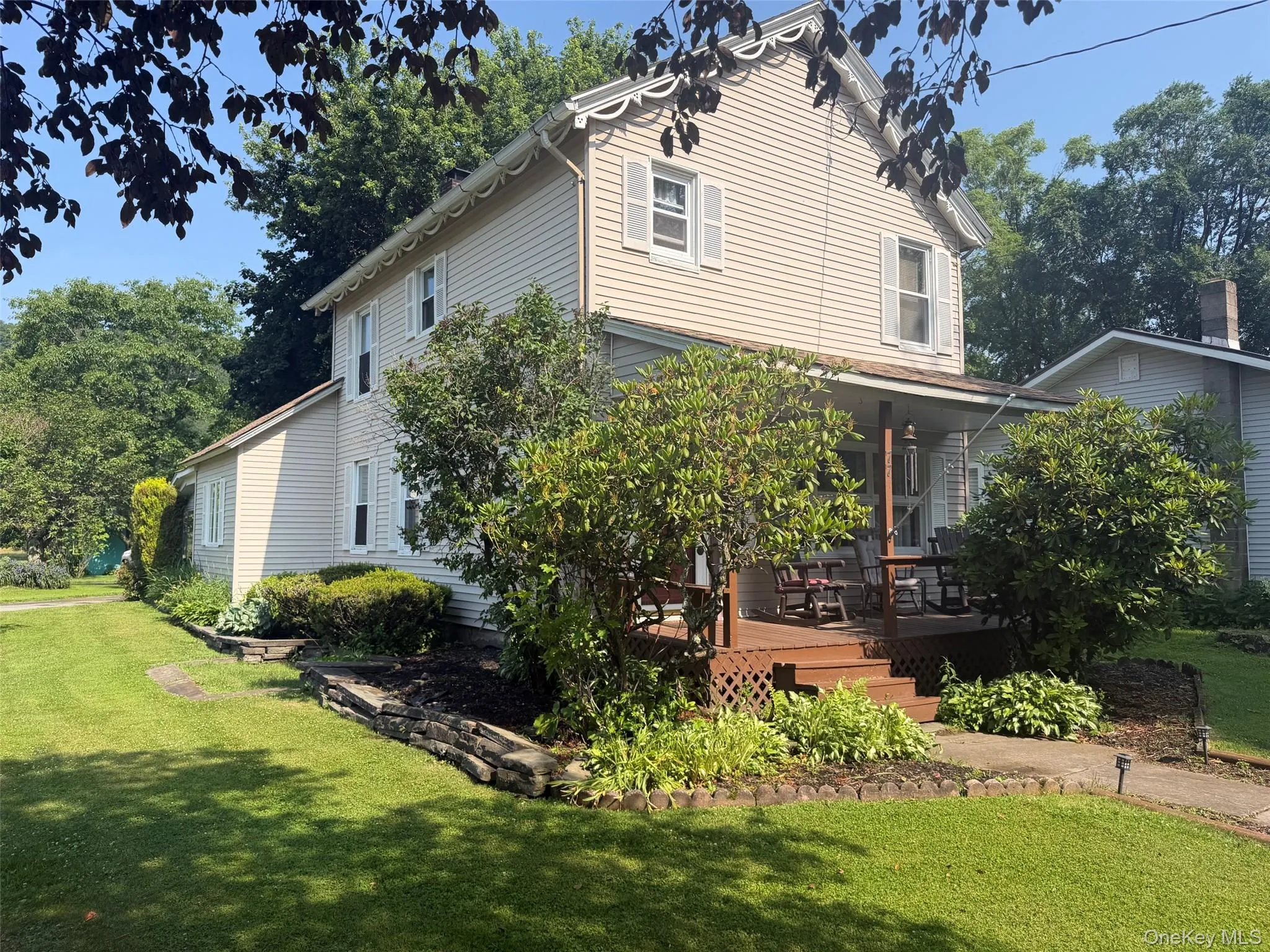 Two-story residence featuring light-colored siding, white window shutters, and decorative scalloped trim under the eaves Two-story residence featuring light-colored siding, white window shutters, and decorative scalloped trim under the eaves