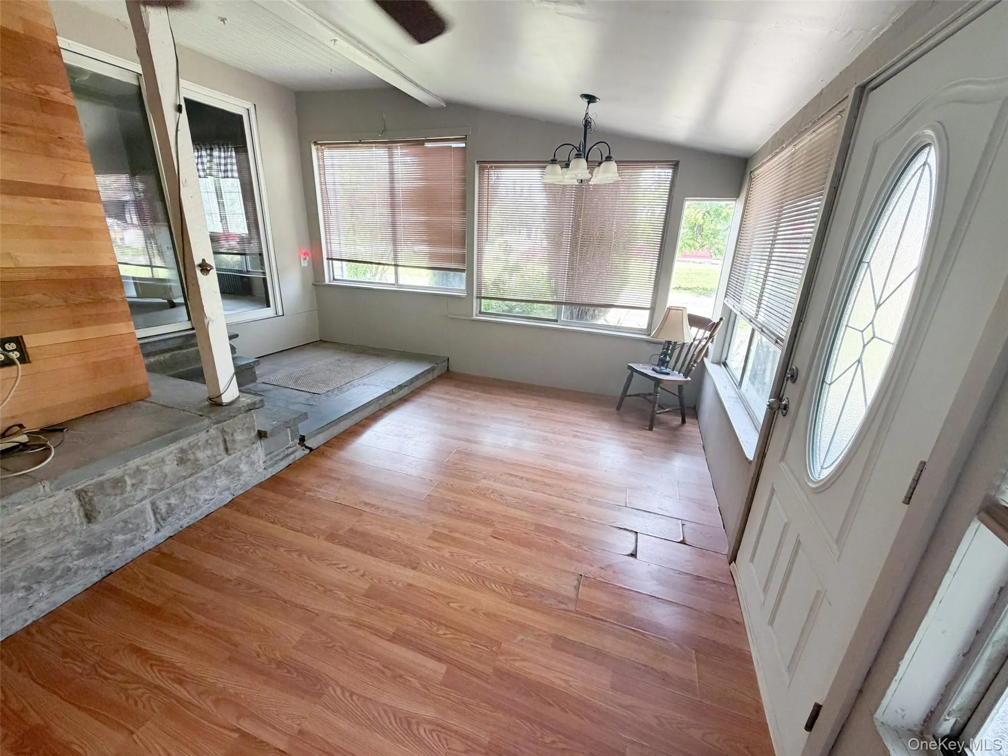 Sunroom featuring wood-finish flooring, multiple windows with blinds, and a decorative glass entry door Sunroom featuring wood-finish flooring, multiple windows with blinds, and a decorative glass entry door